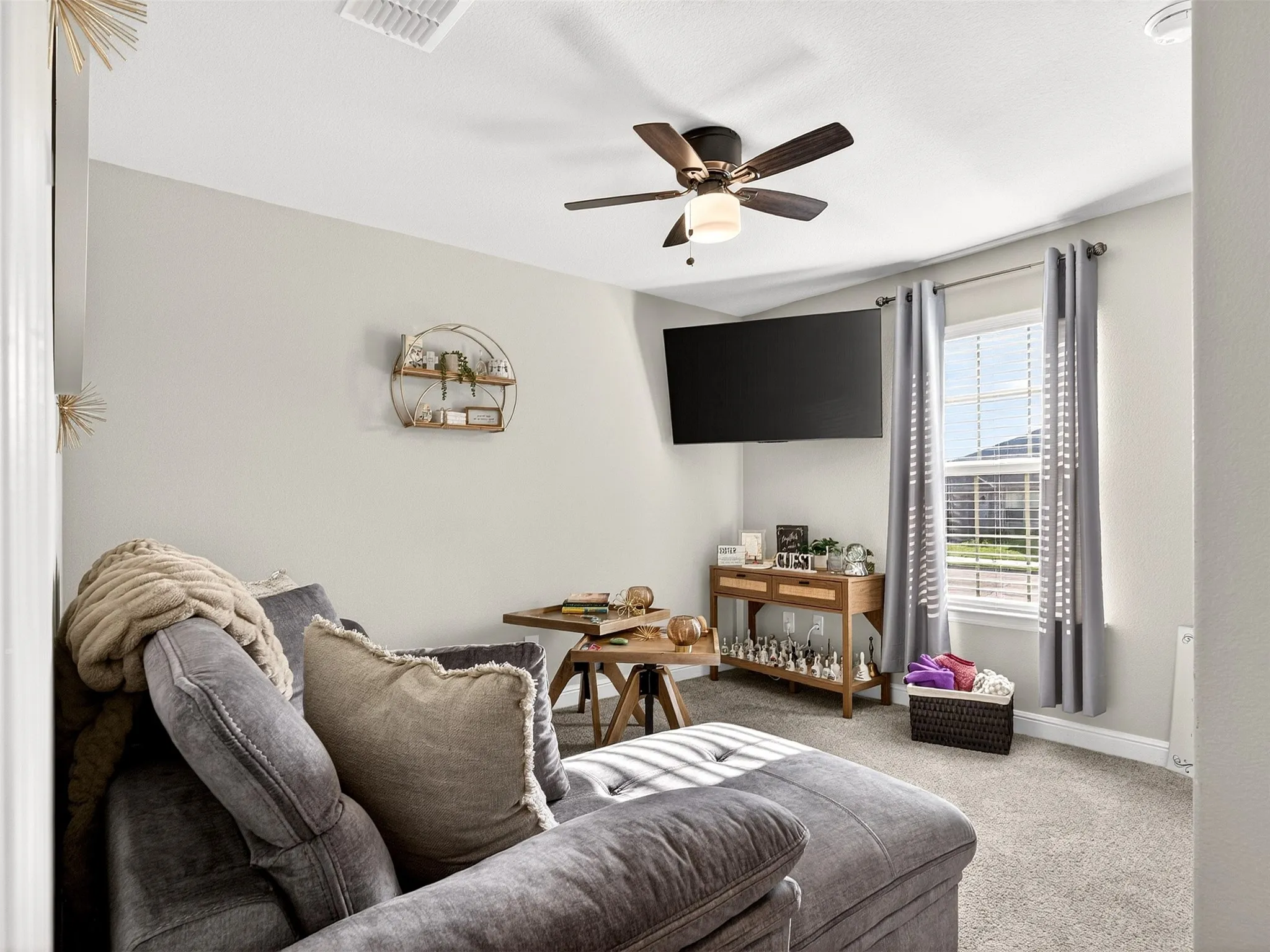 Recessed lighting, ceiling fan with integrated light, wall-mounted television, window with blinds and curtain rods, and carpet flooring