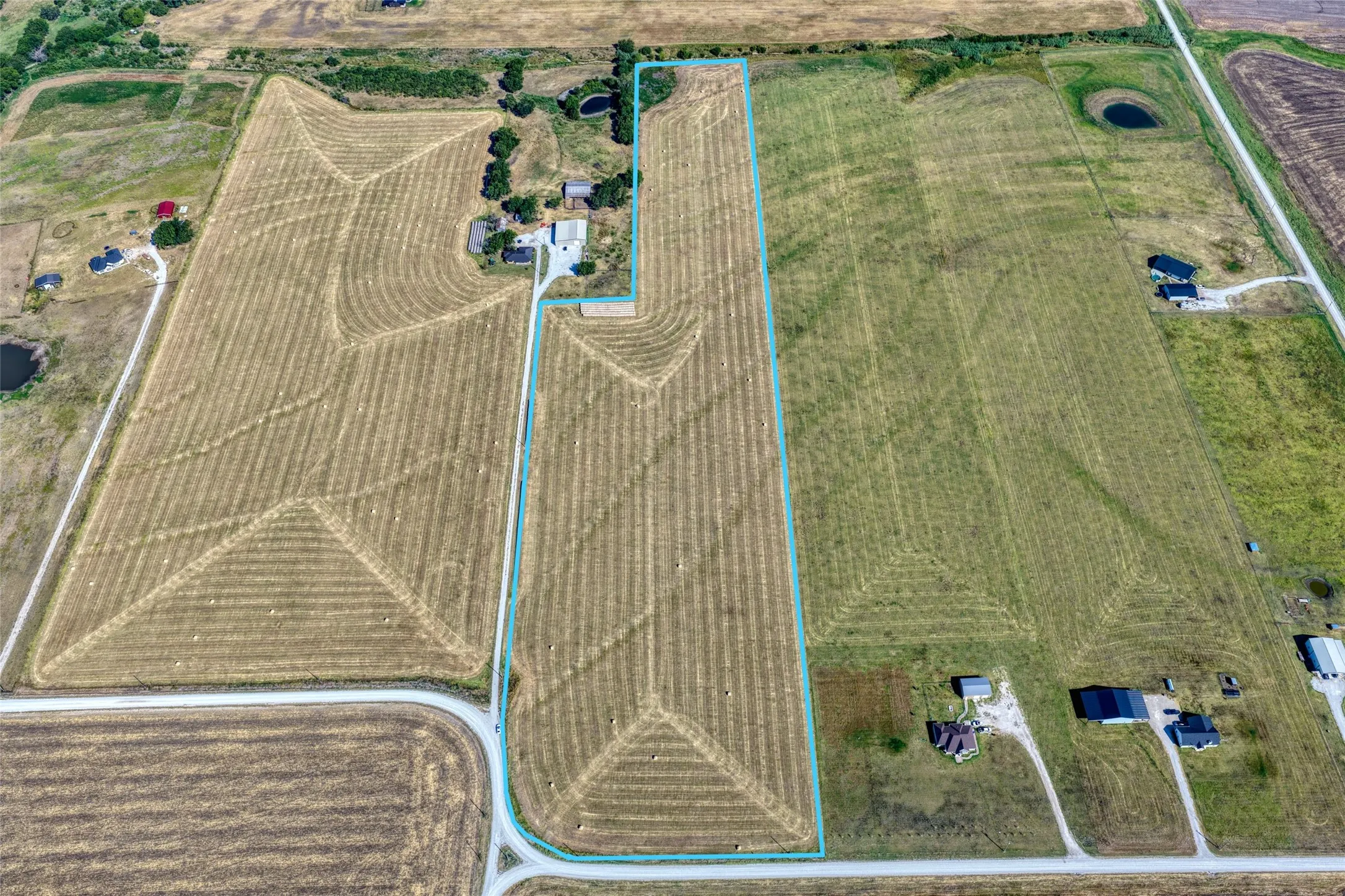 Expansive agricultural land featuring a demarcated property line, adjacent cultivated fields, and surrounding rural properties