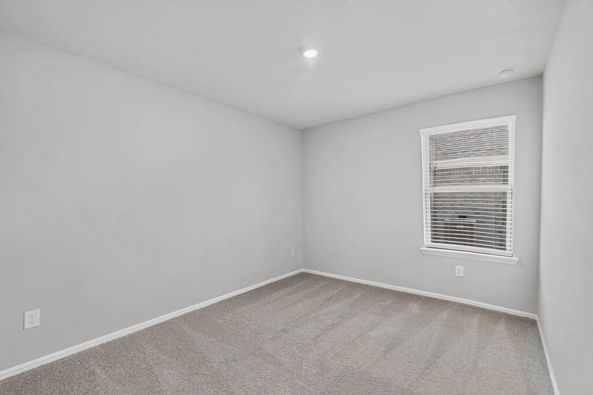Neutral-toned carpeting, light gray wall paint, window with white blinds, and recessed lighting