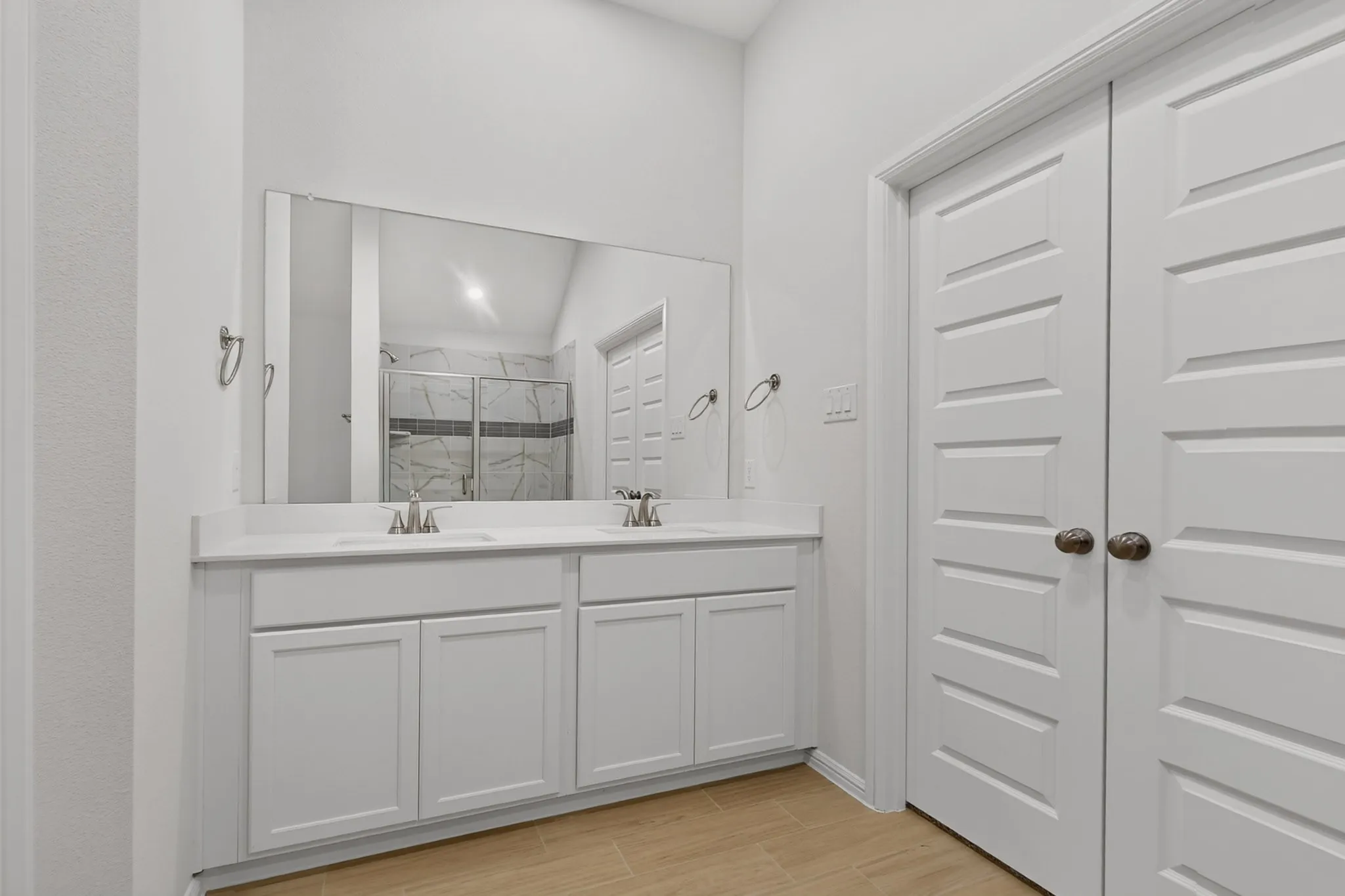 Dual vanity with white cabinetry, integrated sinks, chrome fixtures, and a spacious mirror