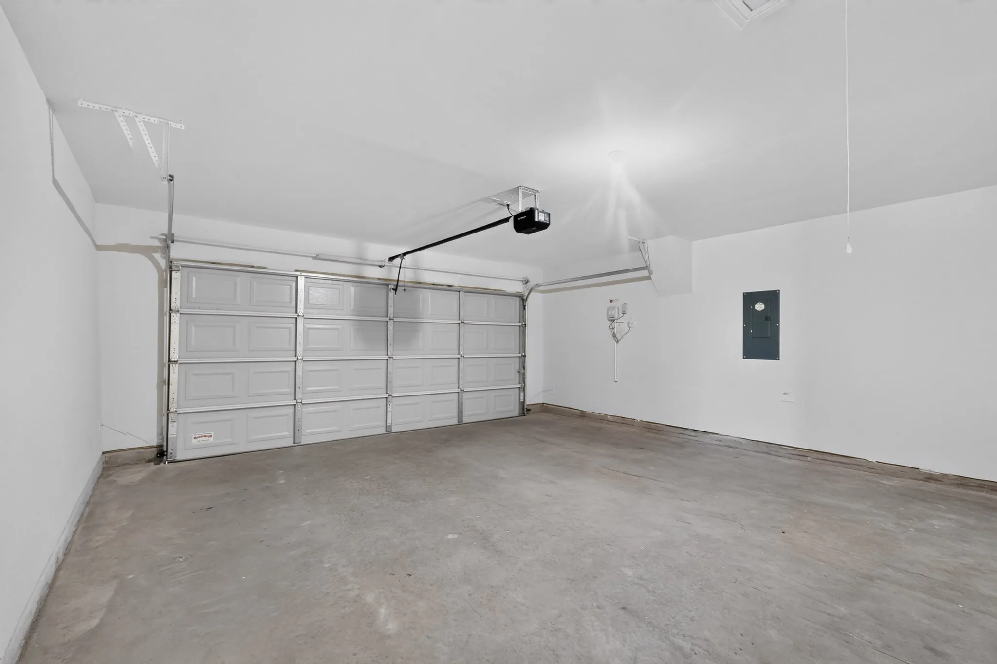 Spacious garage featuring a concrete floor, overhead lighting, and an automatic garage door opener
