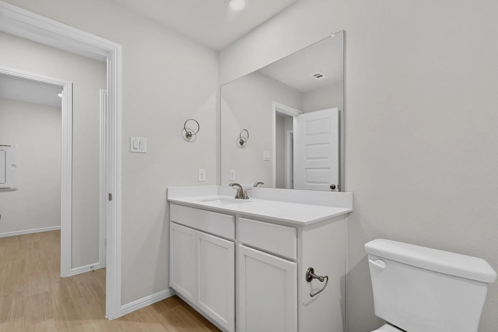 White vanity with a light countertop, integrated sink, and brushed nickel faucet