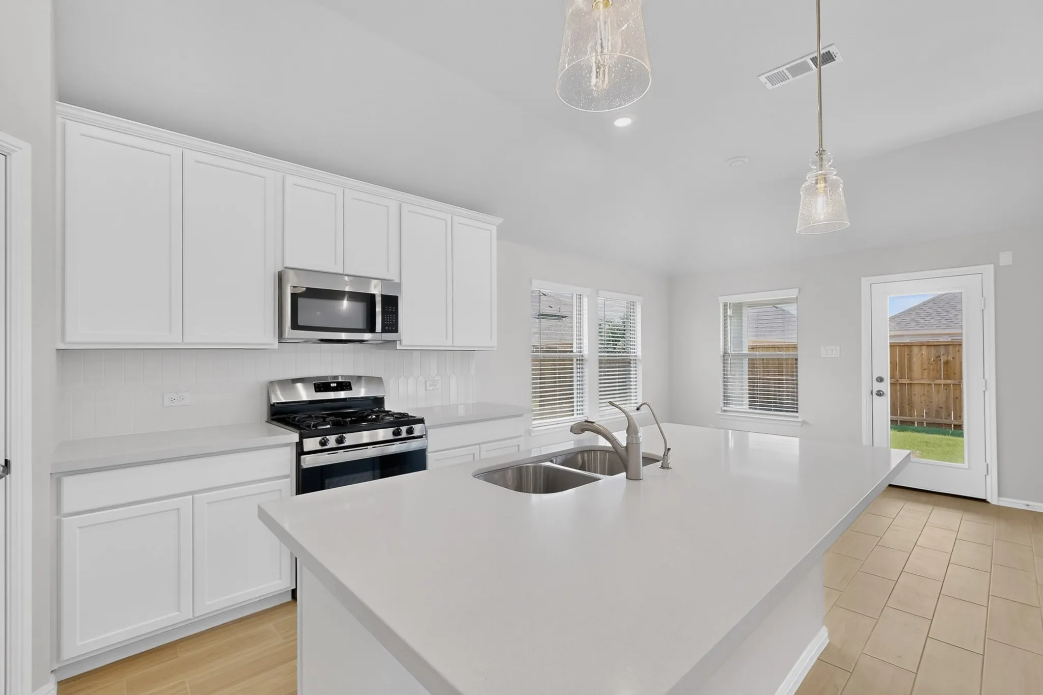 Kitchen featuring a central island with a dual-basin sink, white cabinetry, stainless steel appliances, and tile flooring