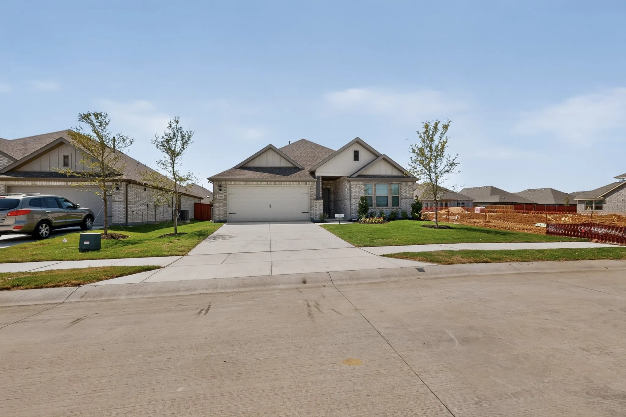 Stone and siding exterior with a two-car garage, concrete driveway, and a landscaped front yard