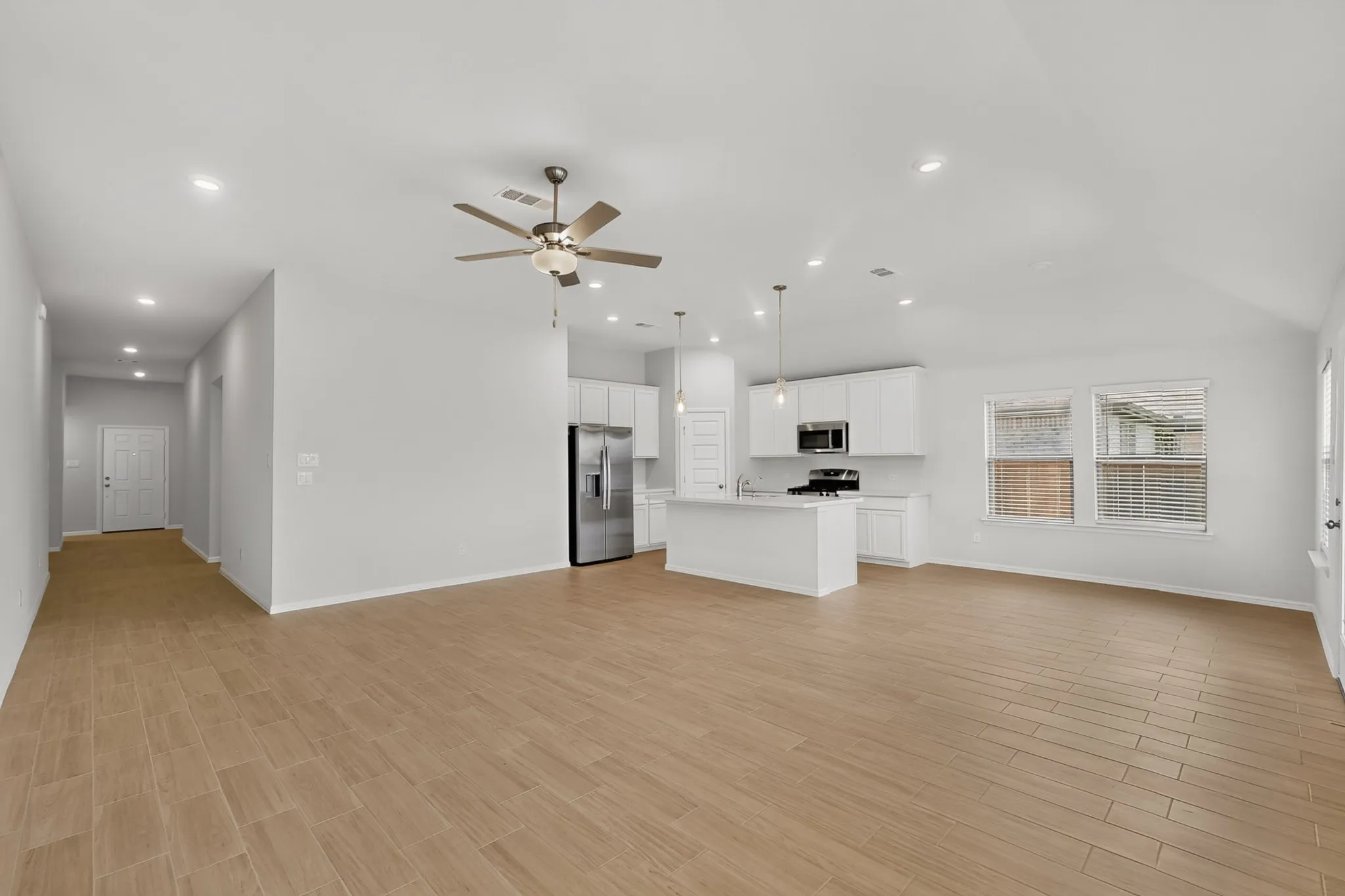 Open-concept living area featuring wood-finish flooring, recessed lighting, and a ceiling fan