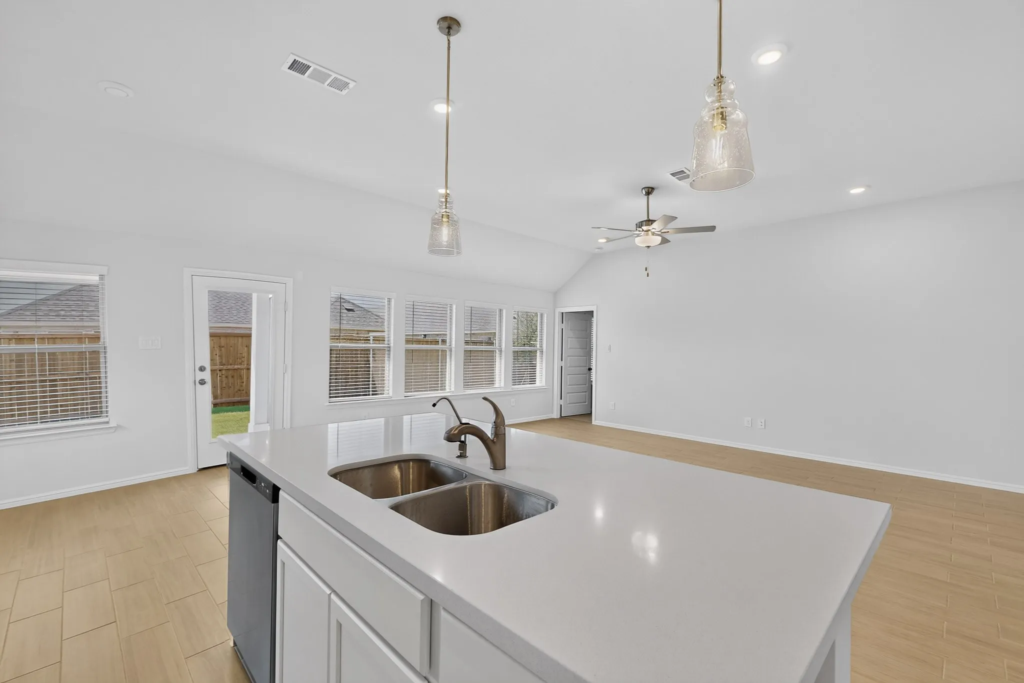 Kitchen island with an undermount dual sink, white countertops, and a built-in dishwasher