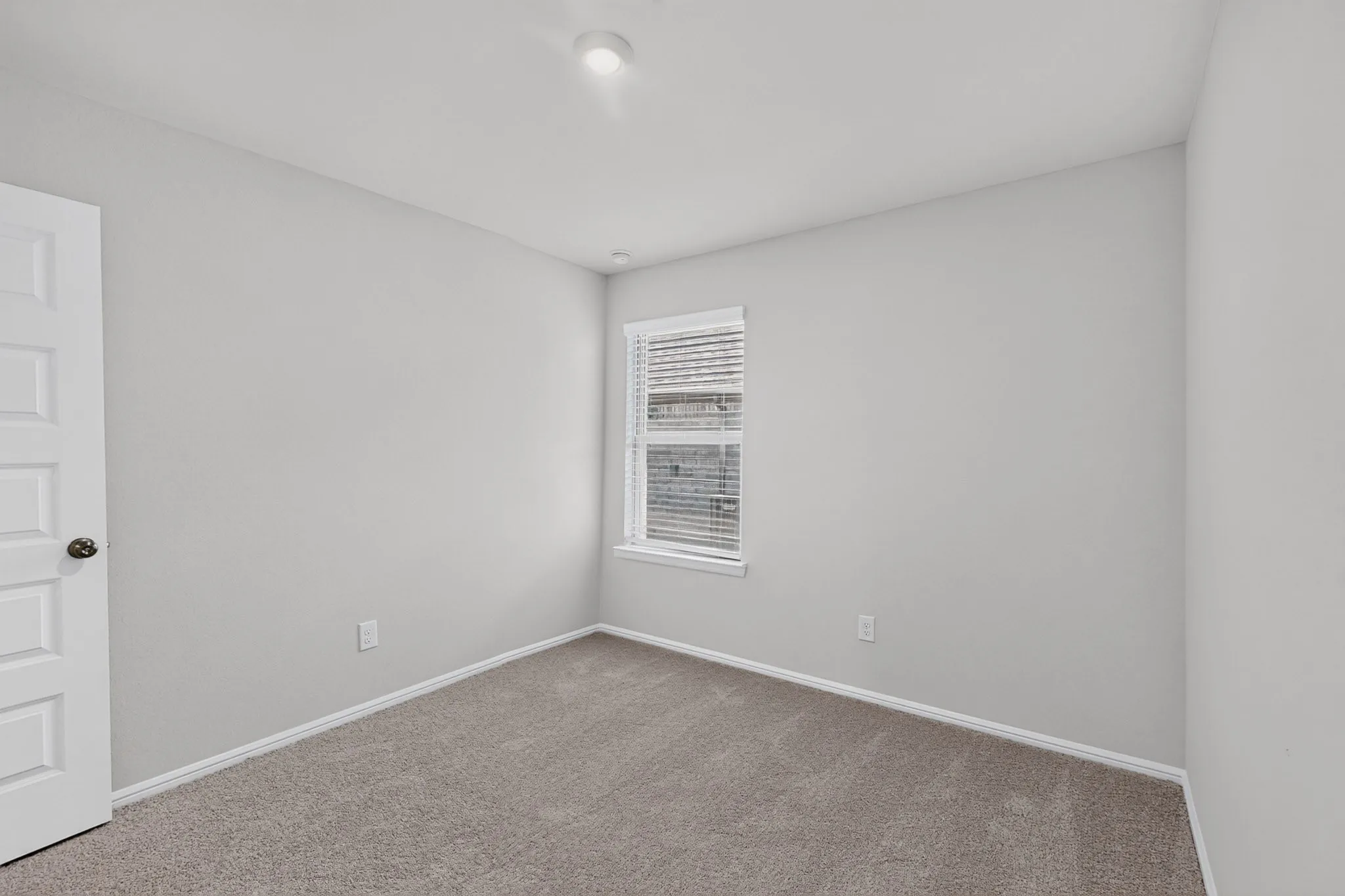 Recessed ceiling light fixture, neutral wall color, window with blinds, and light-toned carpeting