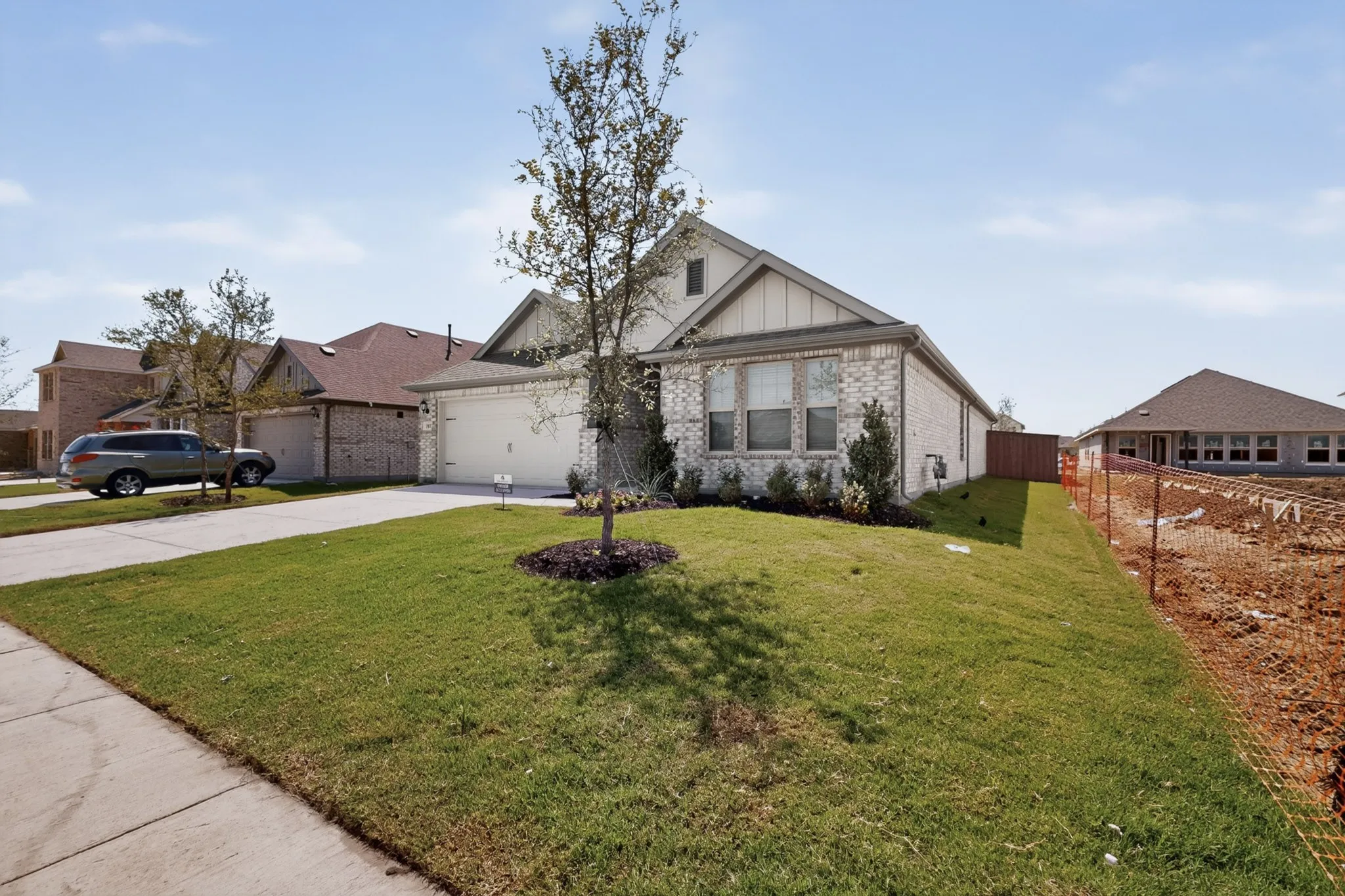 Brick and siding exterior with an attached garage, concrete driveway, and front lawn