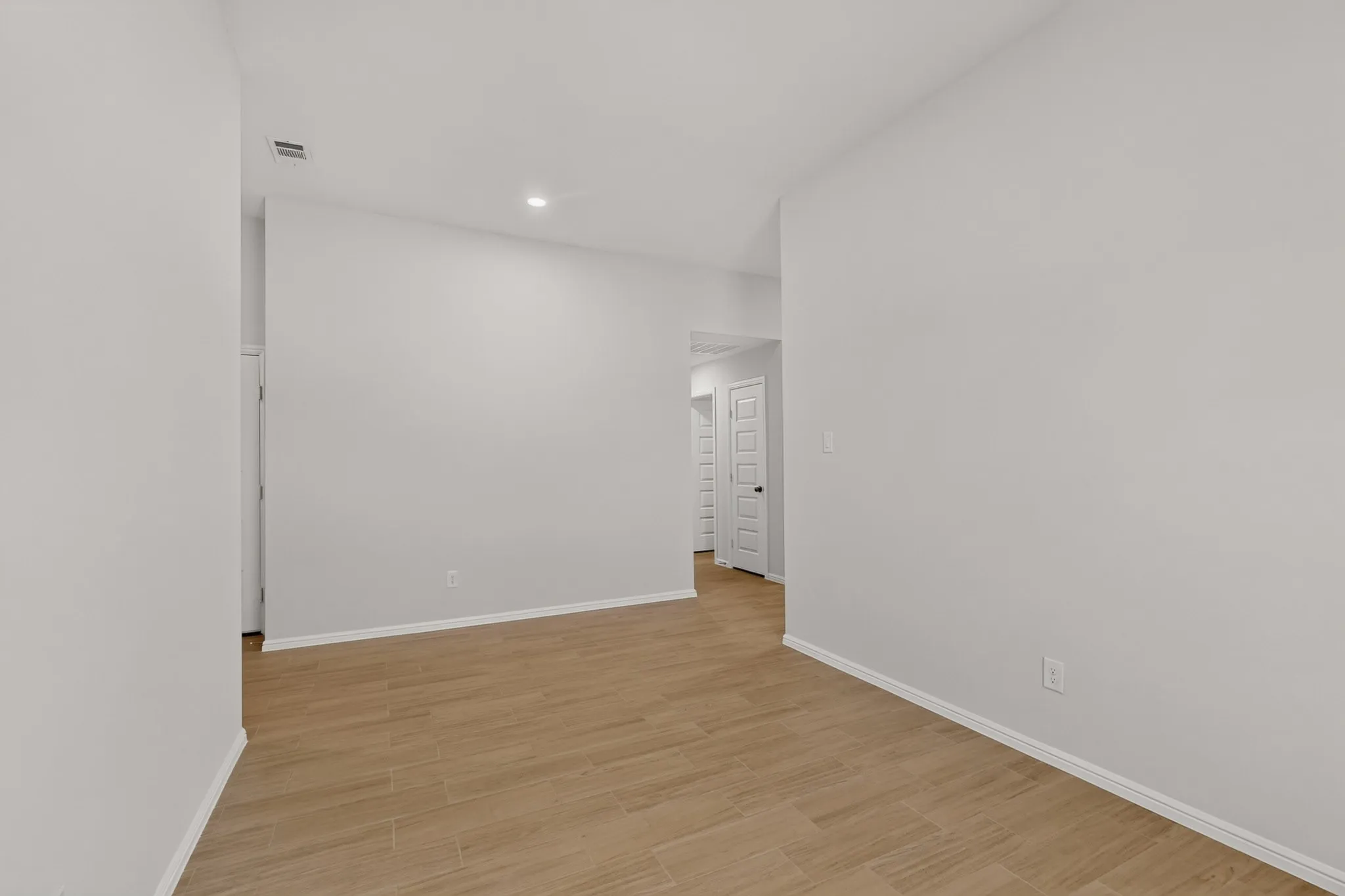 Recessed lighting, light wood-finish flooring, and crisp white walls