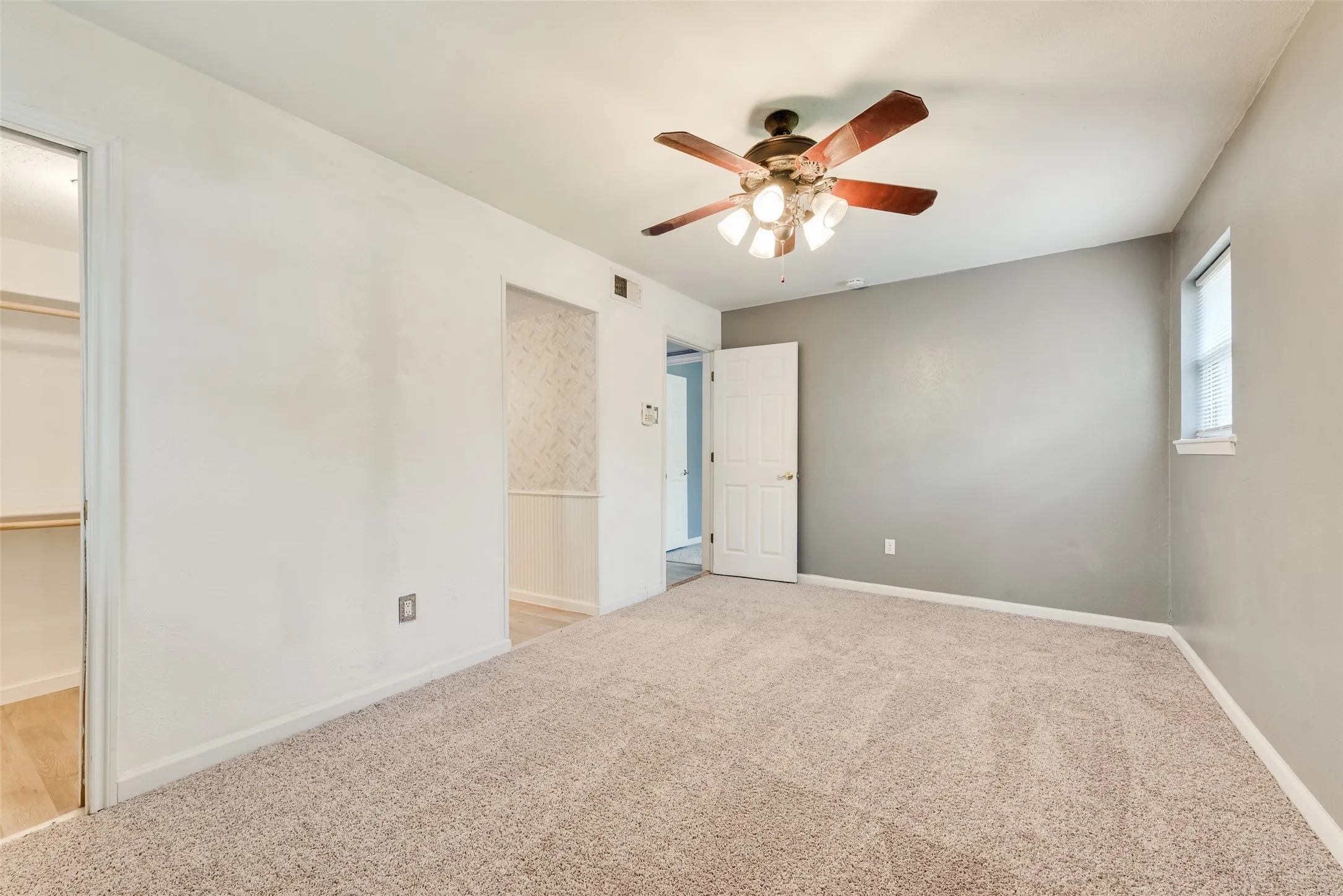 Carpeted flooring, ceiling fan with light fixture, window with blinds, interior door, and closet with shelving