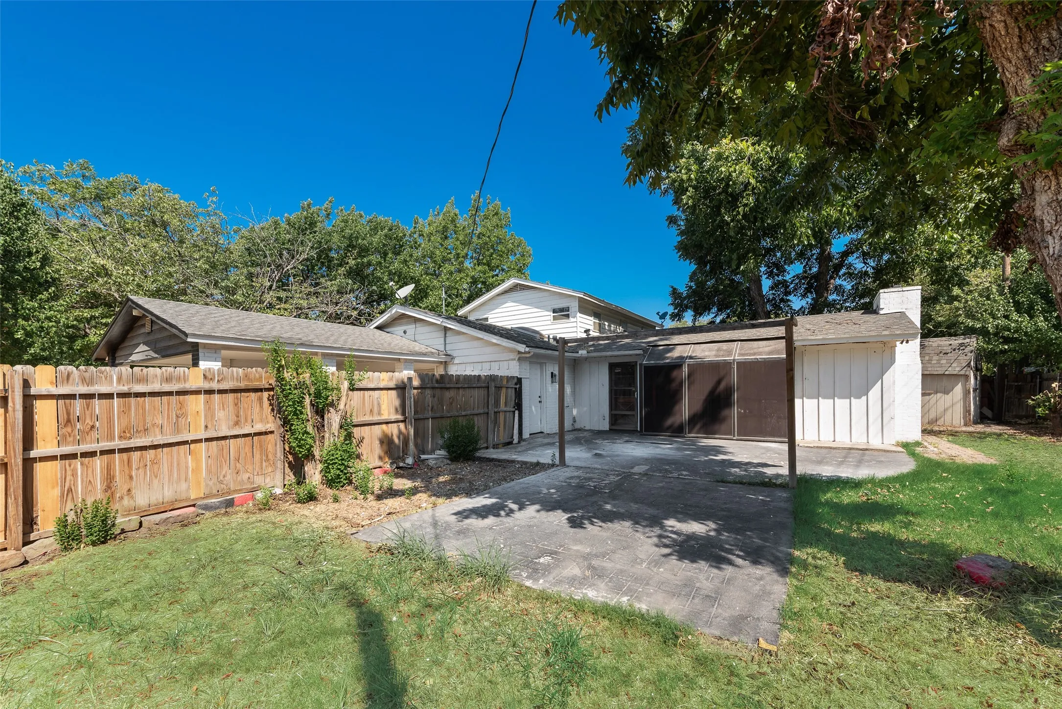 Expansive backyard featuring a wood privacy fence, concrete patio, and mature trees