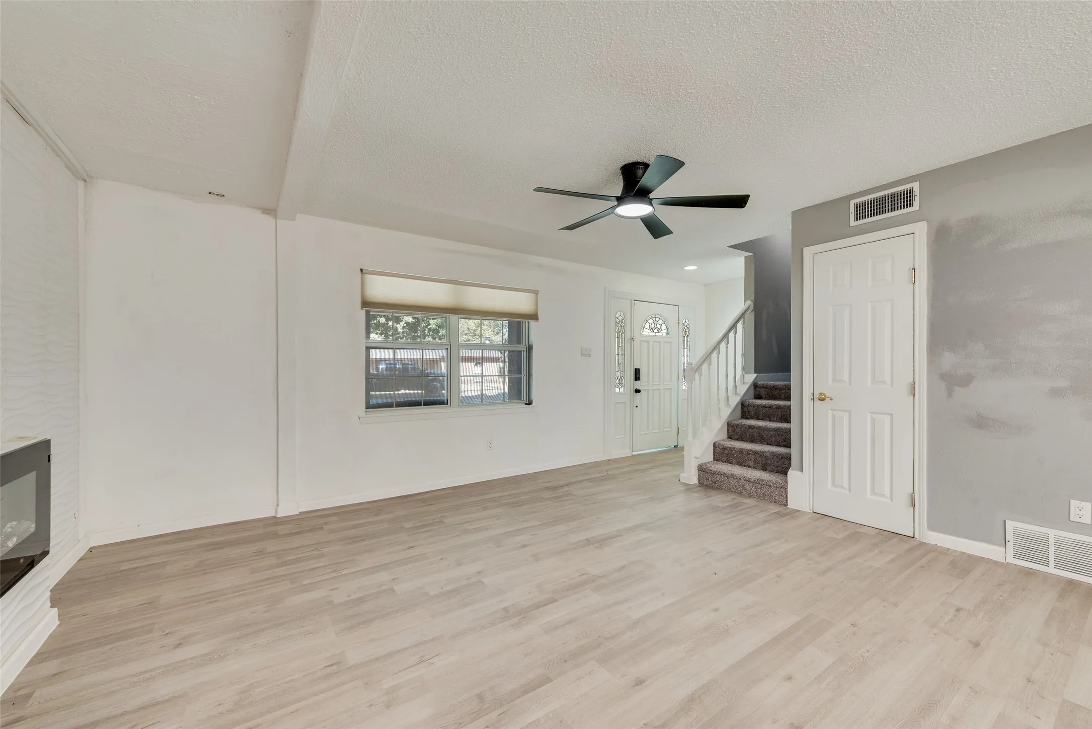 Wood-finish flooring, contemporary ceiling fan, and a built-in electric fireplace