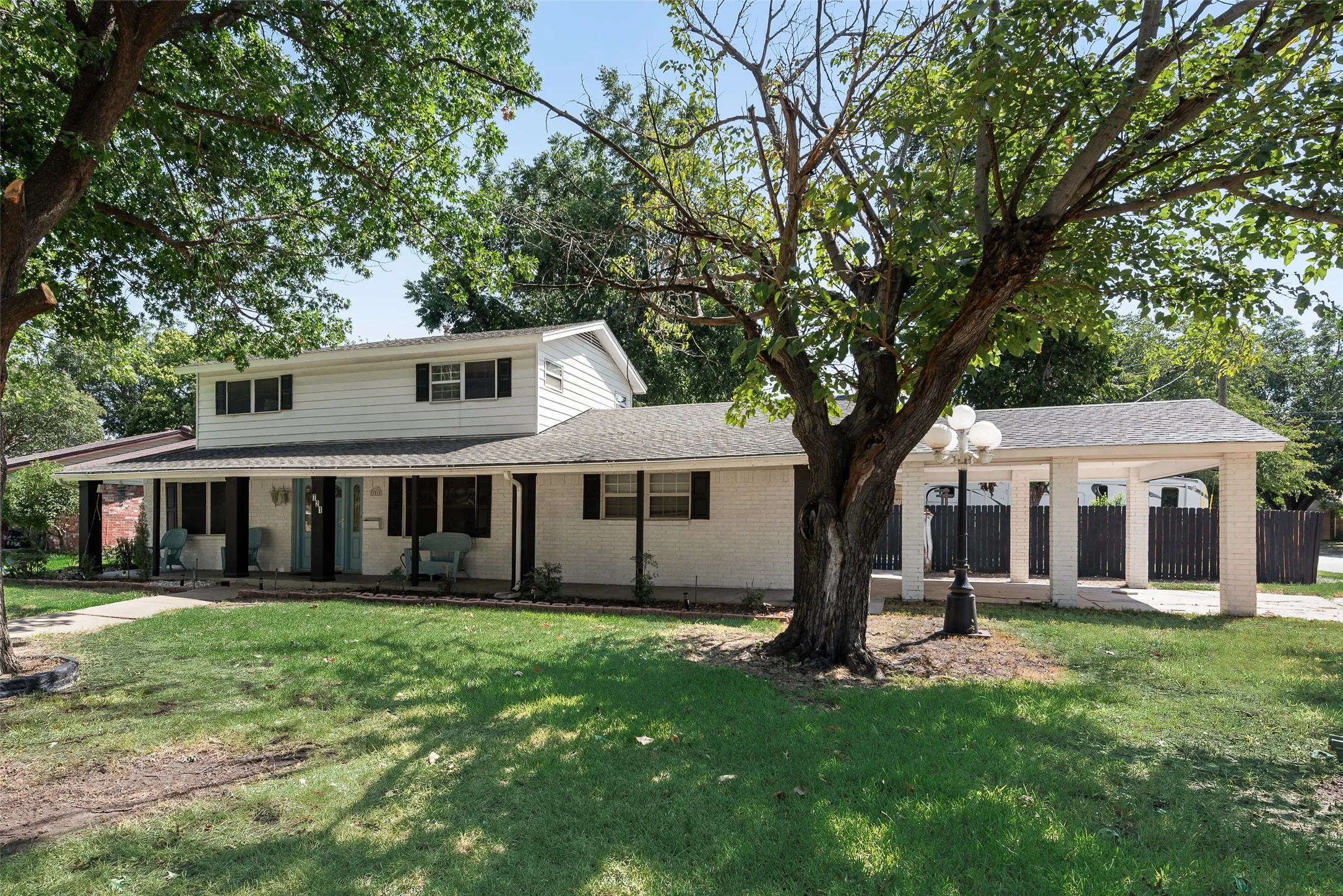 Two-story residence with white siding, covered porch, and black shutters