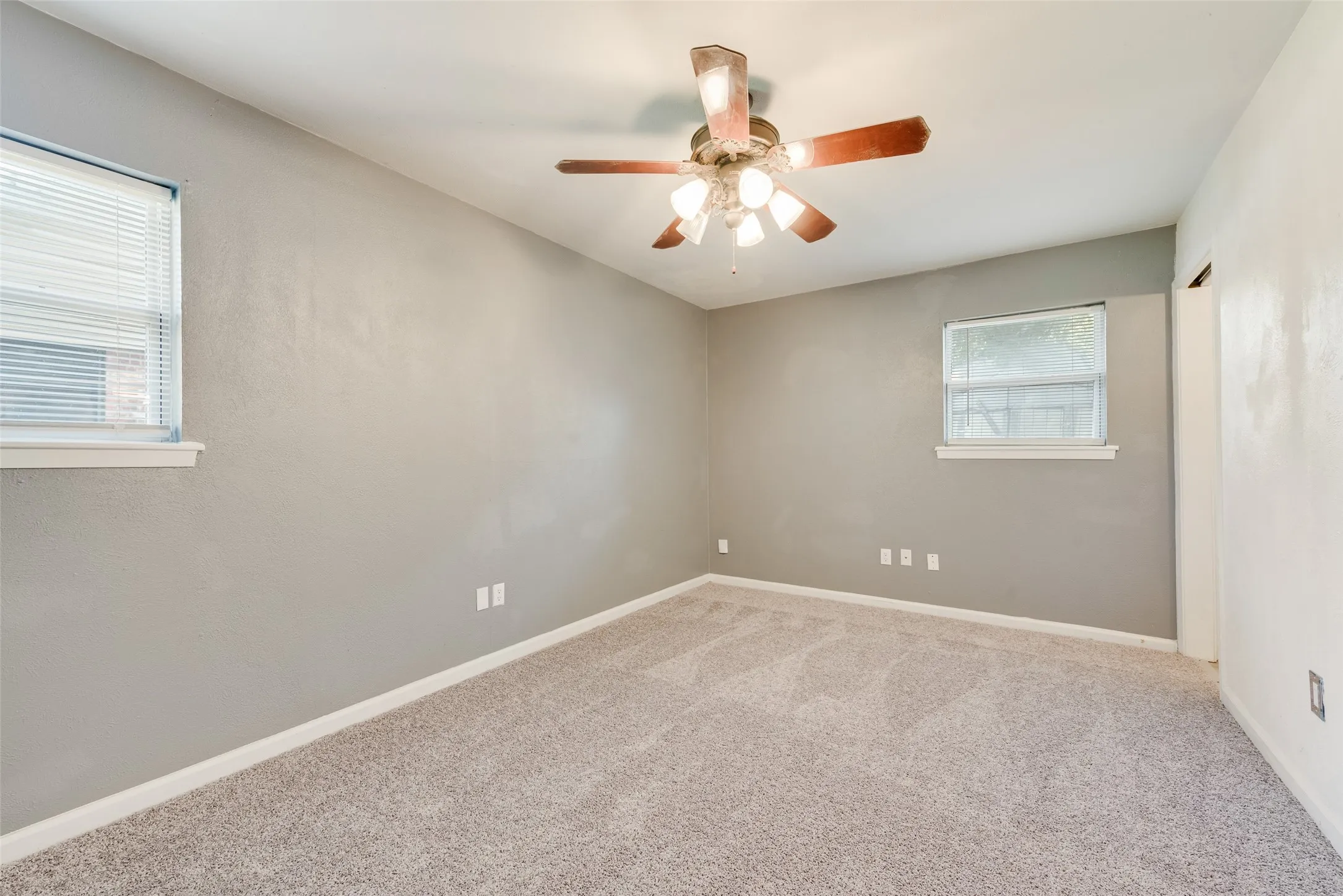 Carpeted flooring, ceiling fan with integrated lighting, multiple windows, neutral wall tones
