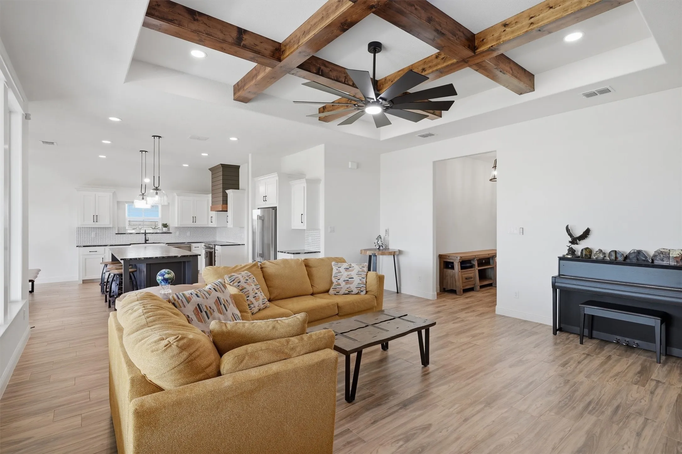 Expansive living area featuring a tray ceiling with wood beams, recessed lighting, and a contemporary ceiling fan