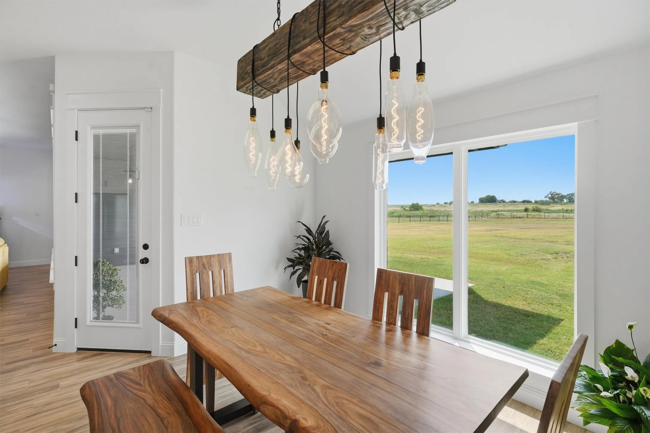 Wood-finish flooring, white walls, and a large window with a distant landscape