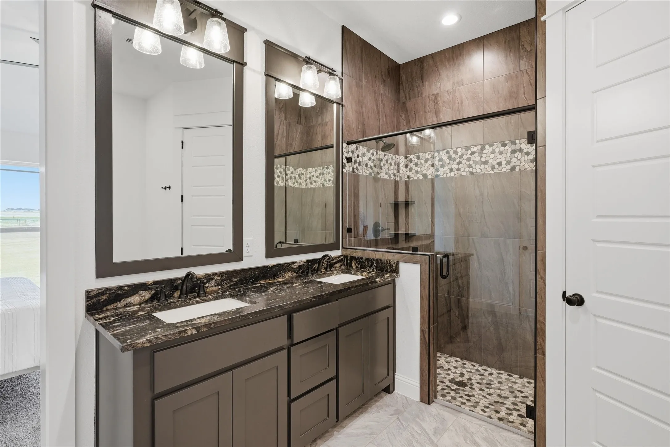 Double vanity with undermount sinks, stone countertops, and dark wood-finish cabinetry