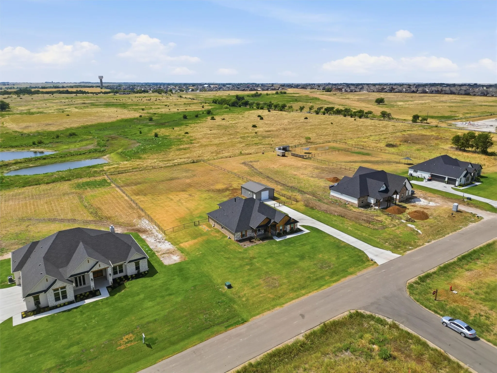 Expansive green lawn, paved driveway, single-story residence, asphalt shingle roof, two-car garage
