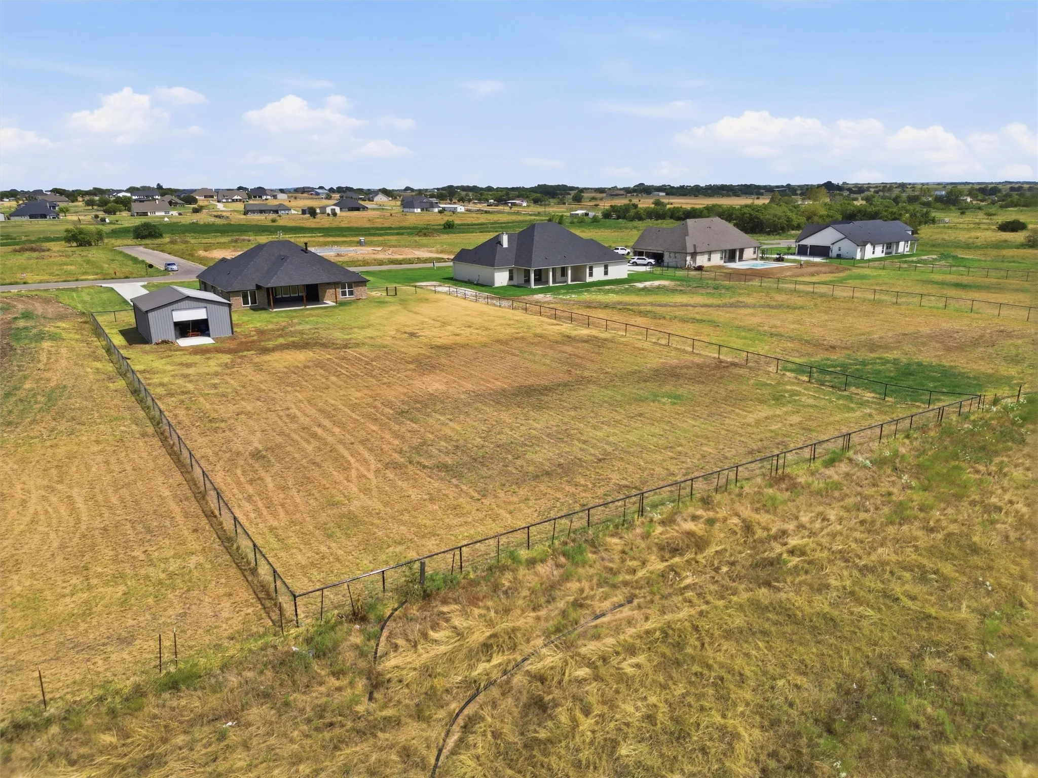 Expansive land parcel featuring perimeter fencing and a dedicated outbuilding