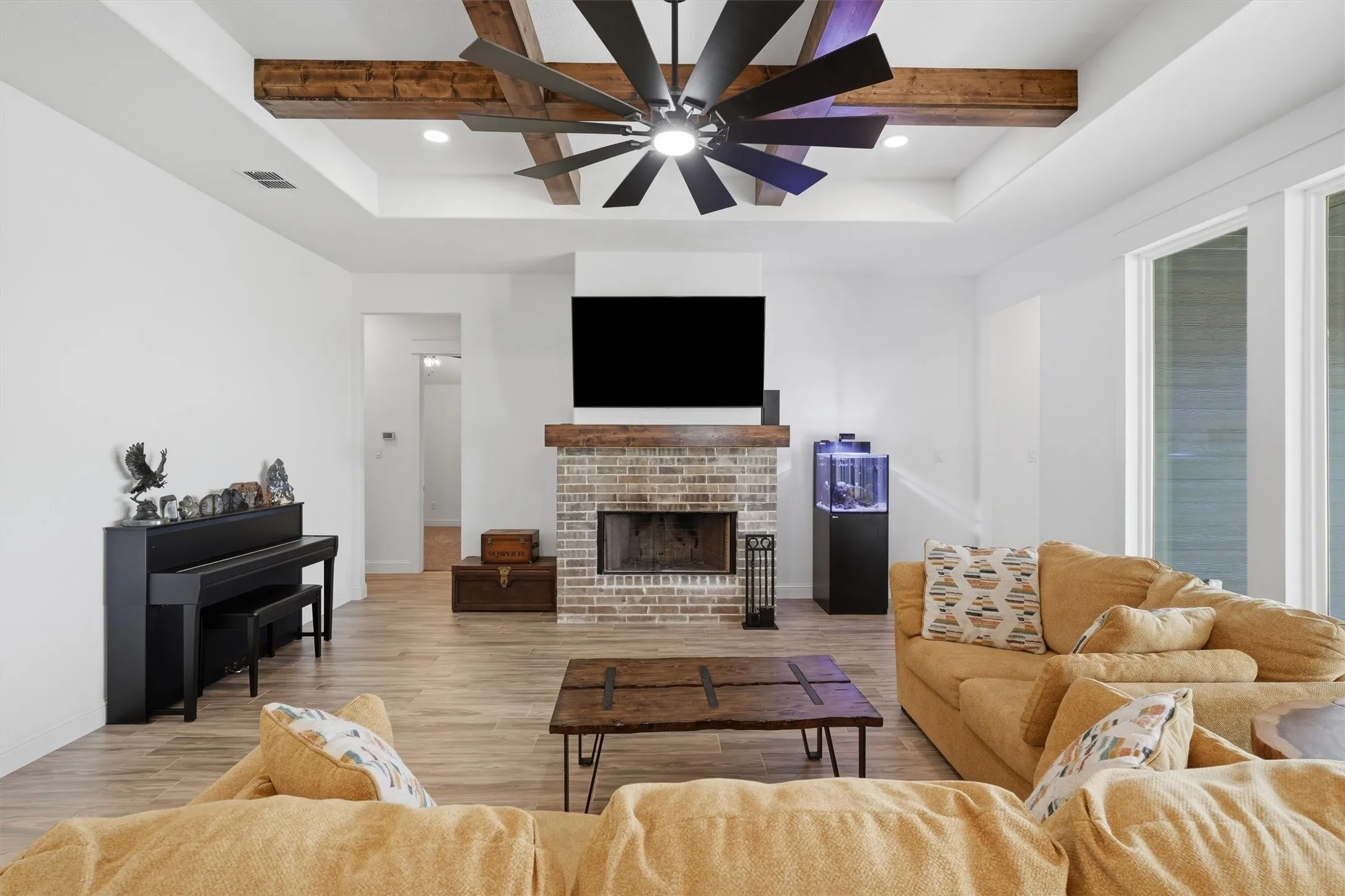 Tray ceiling with dark wood-finish beams, recessed lighting, and a large ceiling fan