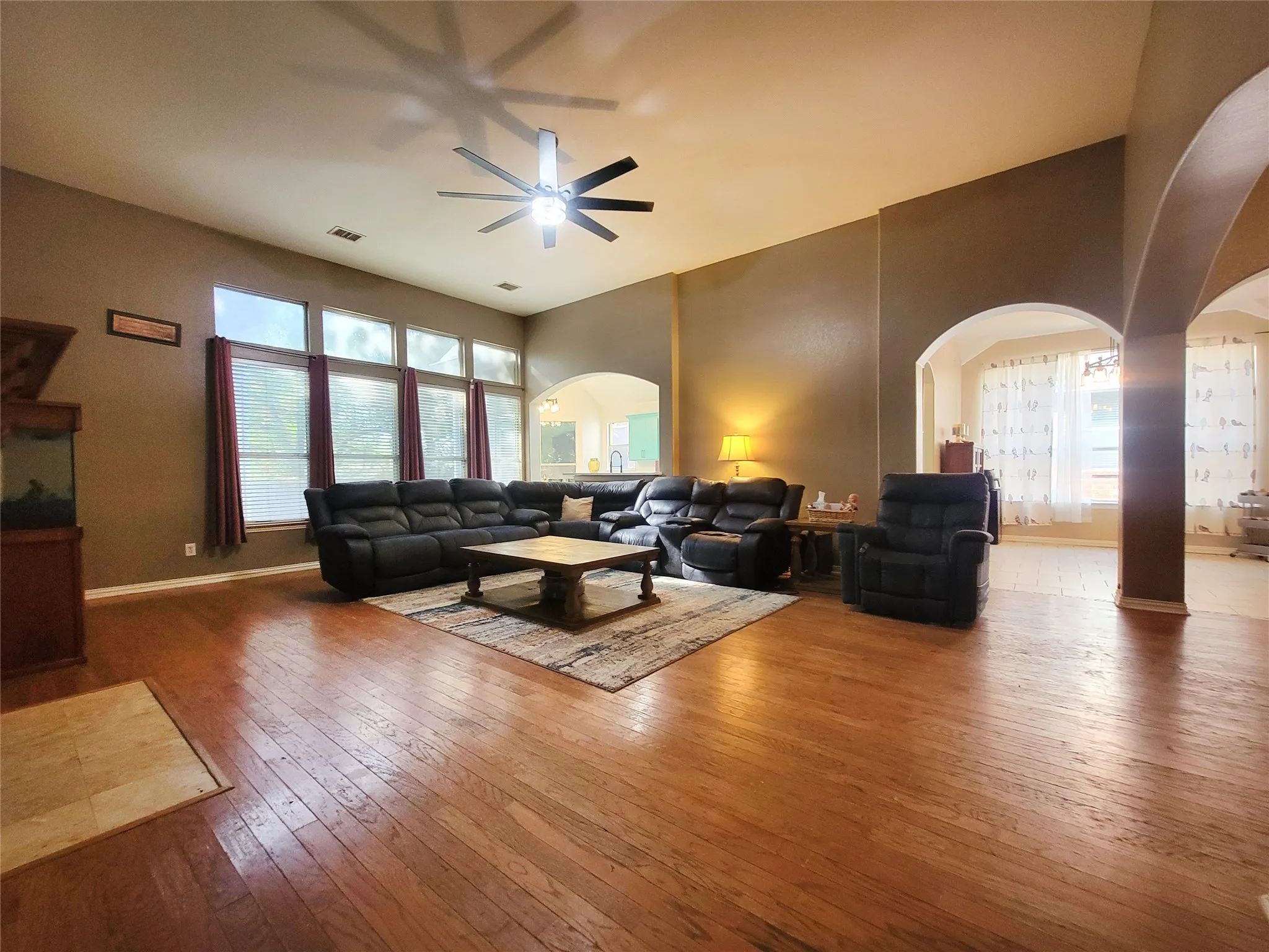 Spacious living area featuring wood-finish flooring, vaulted ceilings, and a series of arched doorways