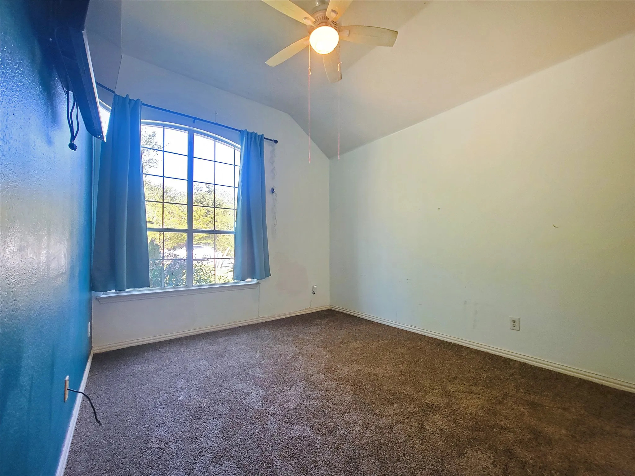 Brand New Carpet Arched window with gridded panes, sloped ceiling, and ceiling fan