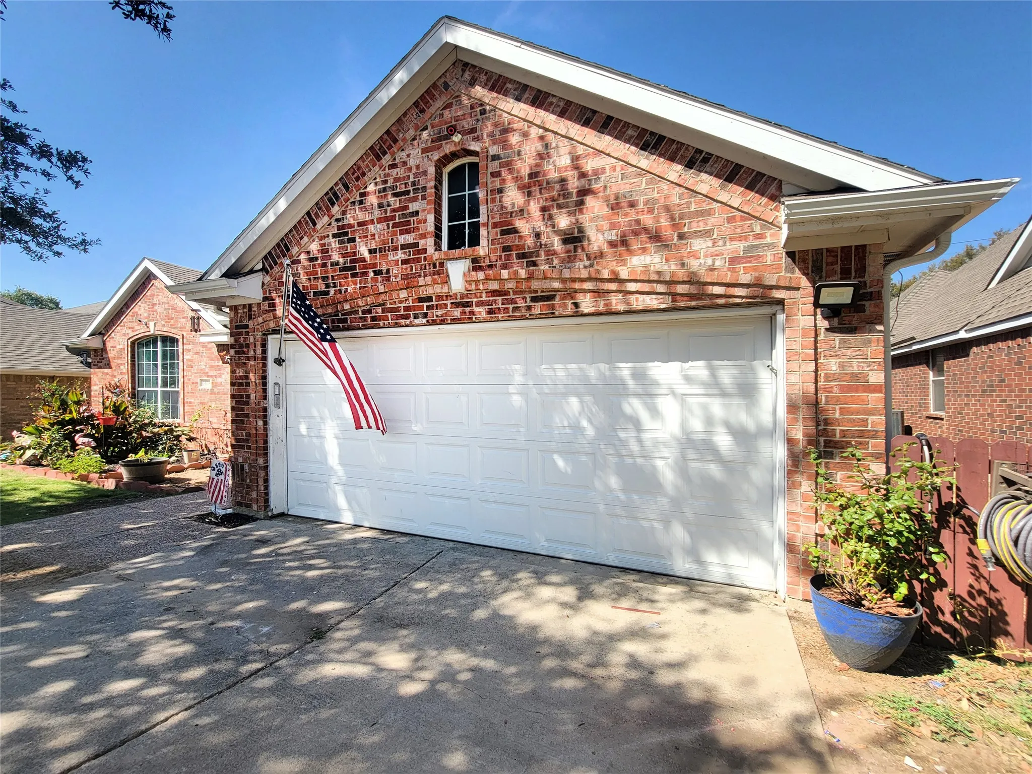Brick exterior with white trim, featuring an arched window and a segmented garage door