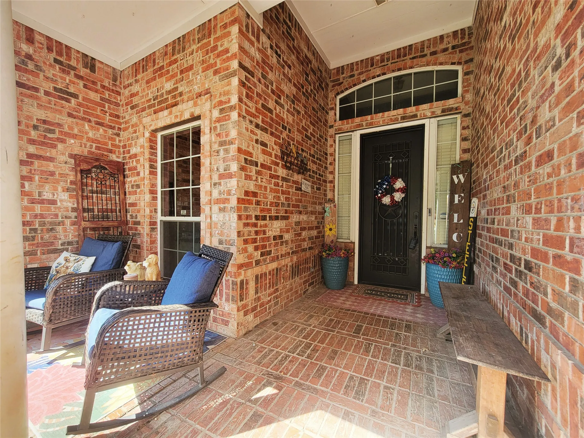 Brick exterior with a covered porch, solid entry door, transom window, and sidelight windows