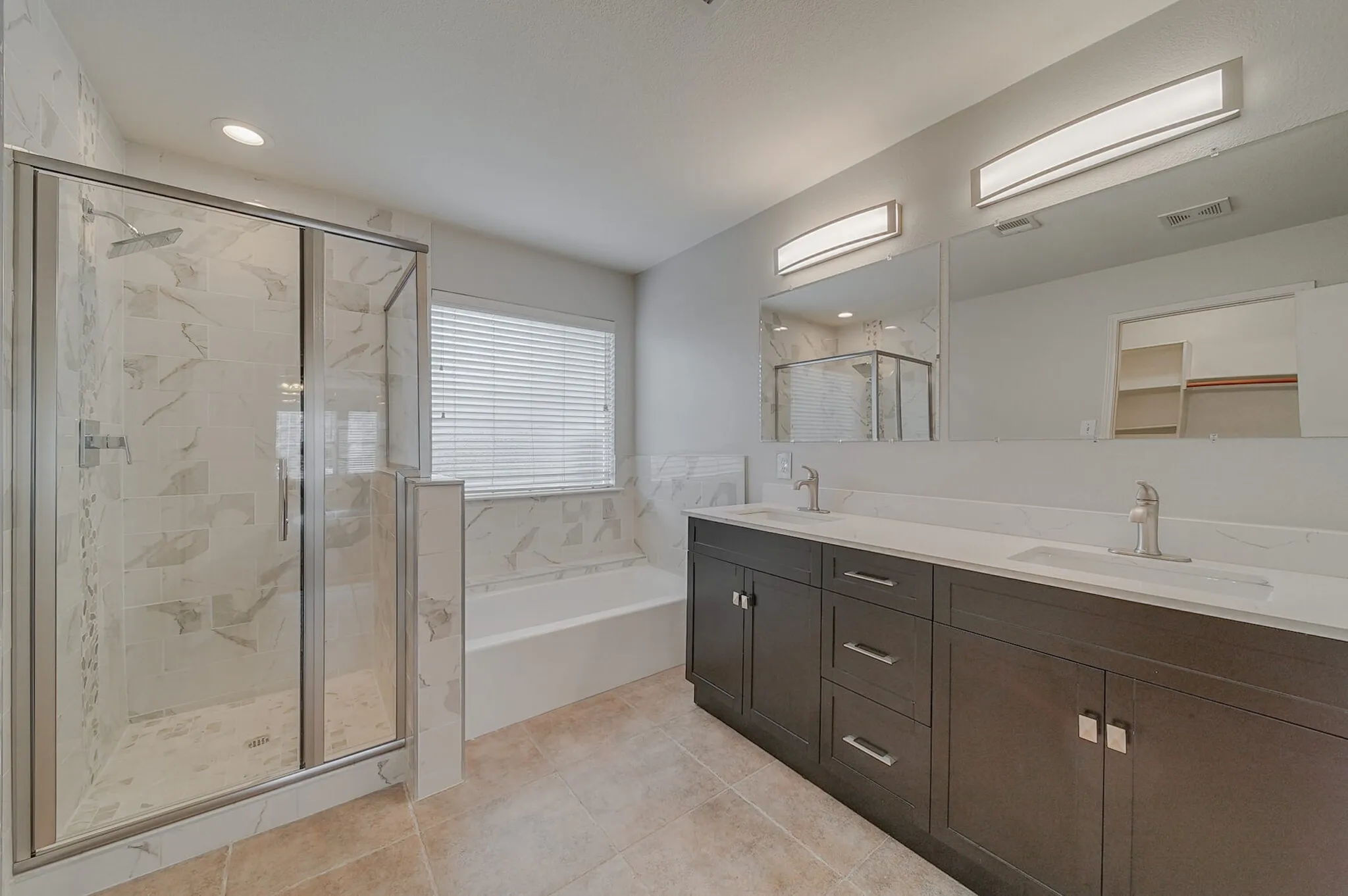 Dual vanity with undermount sinks, frameless glass shower enclosure, built-in soaking tub, and tile flooring