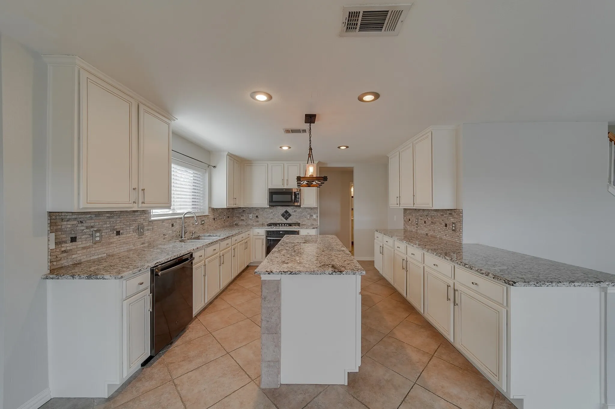 Kitchen featuring an island, white cabinetry, integrated appliances, recessed lighting, and tile flooring