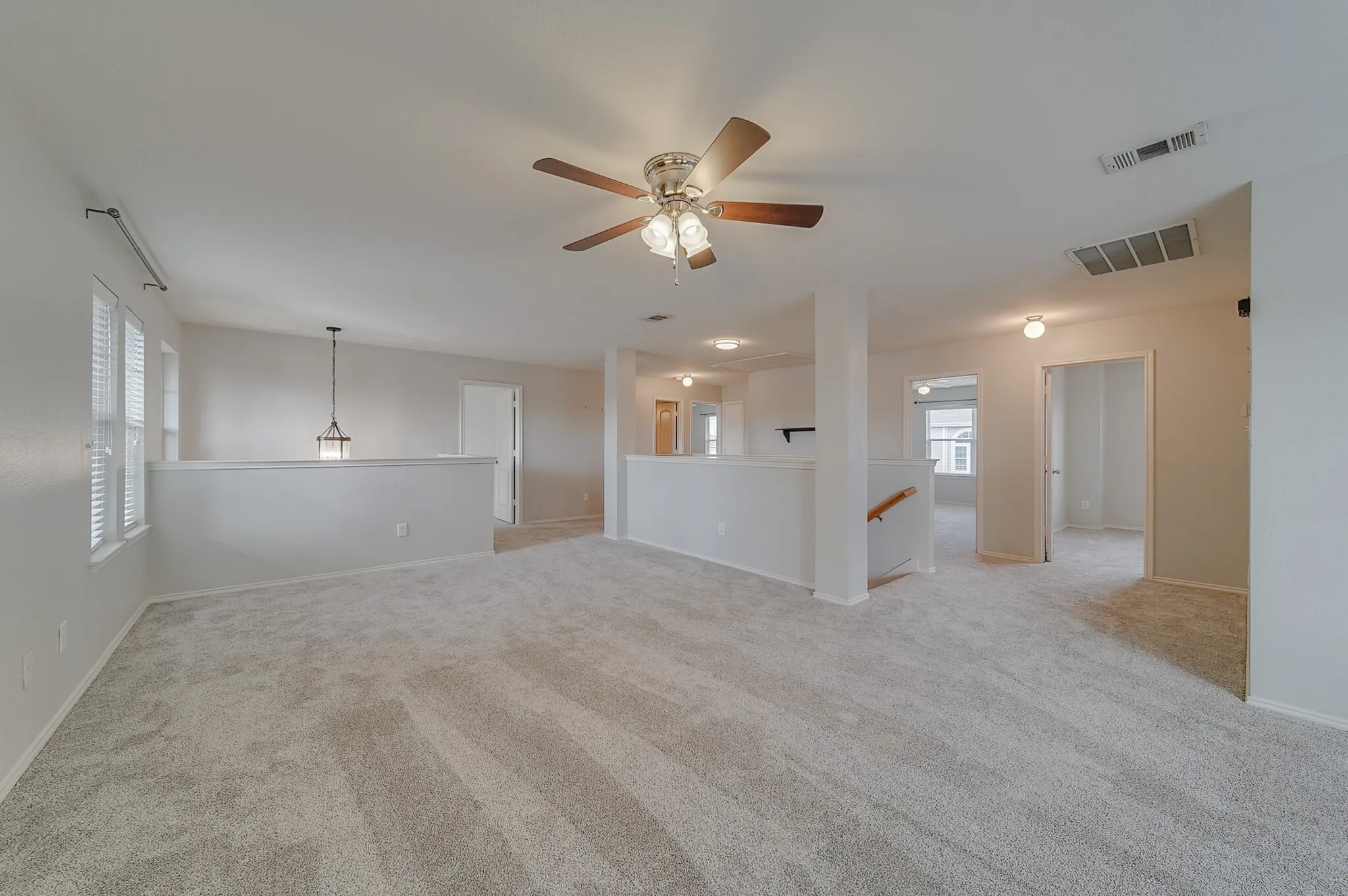 Spacious carpeted area with a ceiling fan, multiple windows with blinds, and recessed lighting