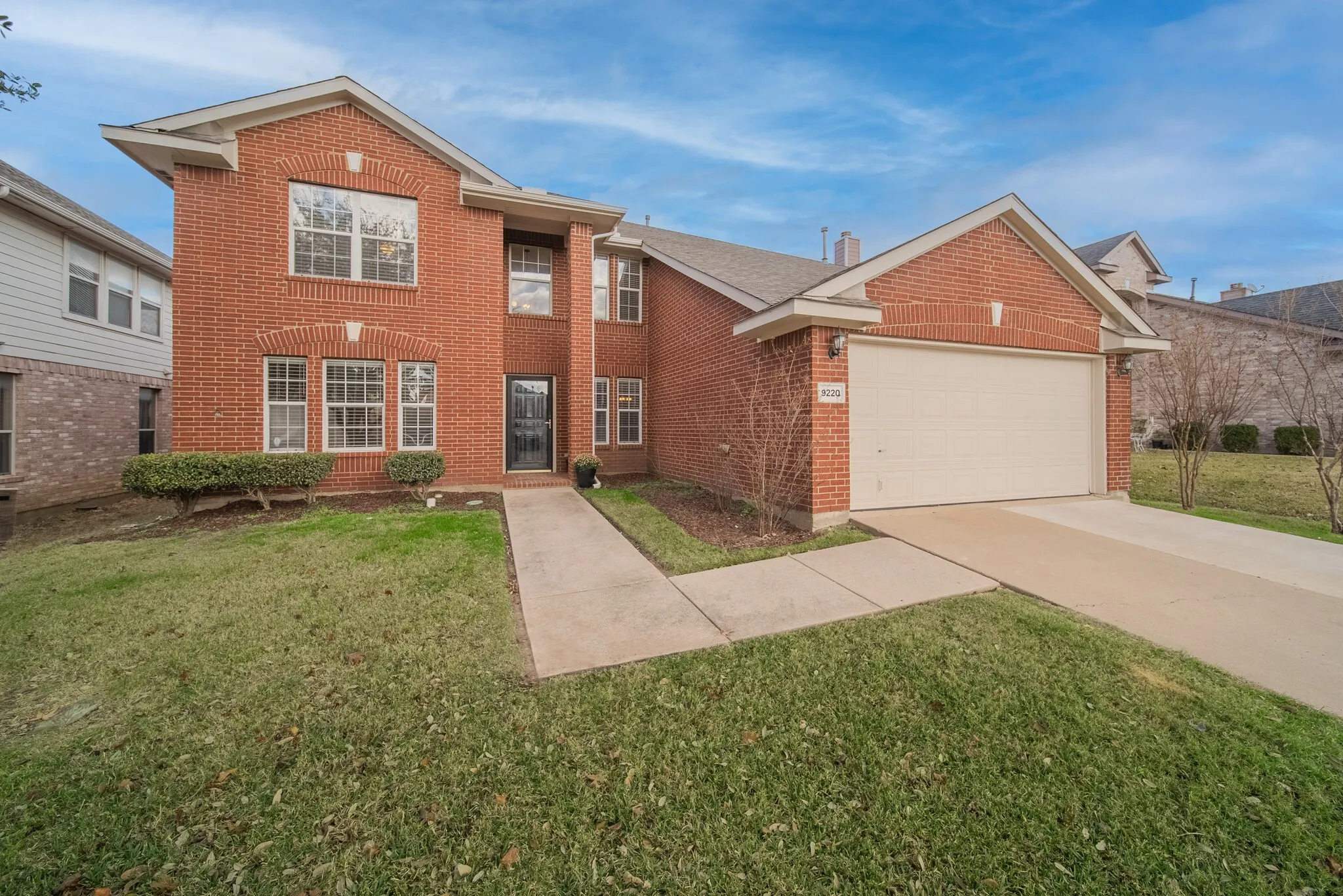 Brick exterior, attached two-car garage, concrete driveway, front walkway, and established front landscaping