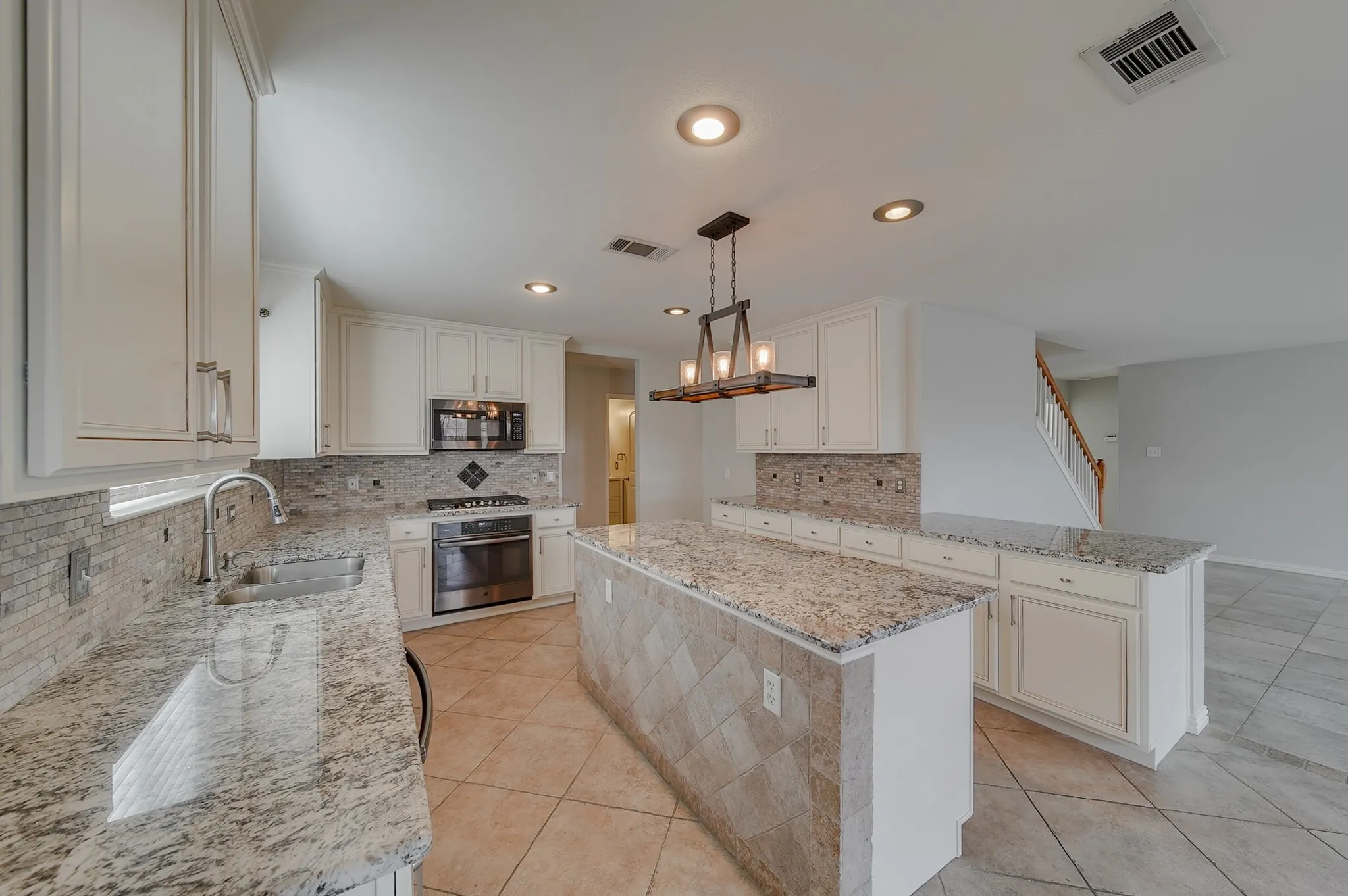 Spacious kitchen featuring white cabinetry, stone countertops, stainless steel appliances, a tiled backsplash, and recessed lighting