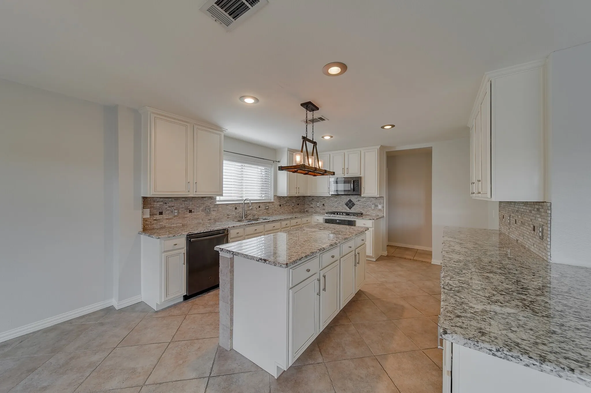 Kitchen featuring an island, white cabinetry, granite countertops, tile flooring, and stainless steel appliances