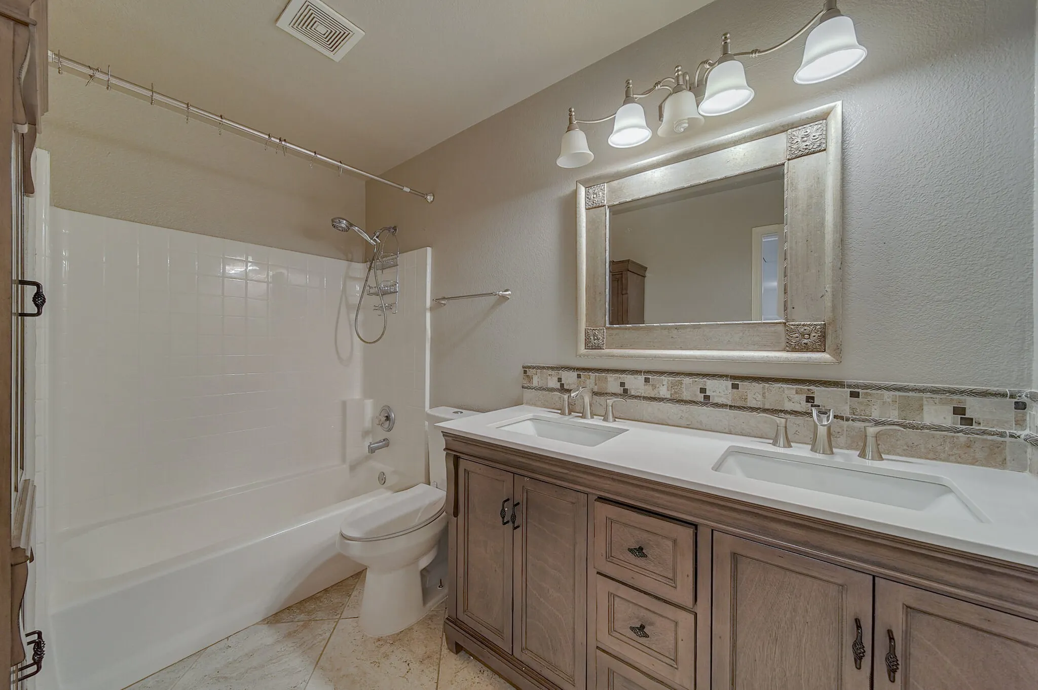 Double vanity with undermount sinks, stone-look countertop, and a decorative tile backsplash