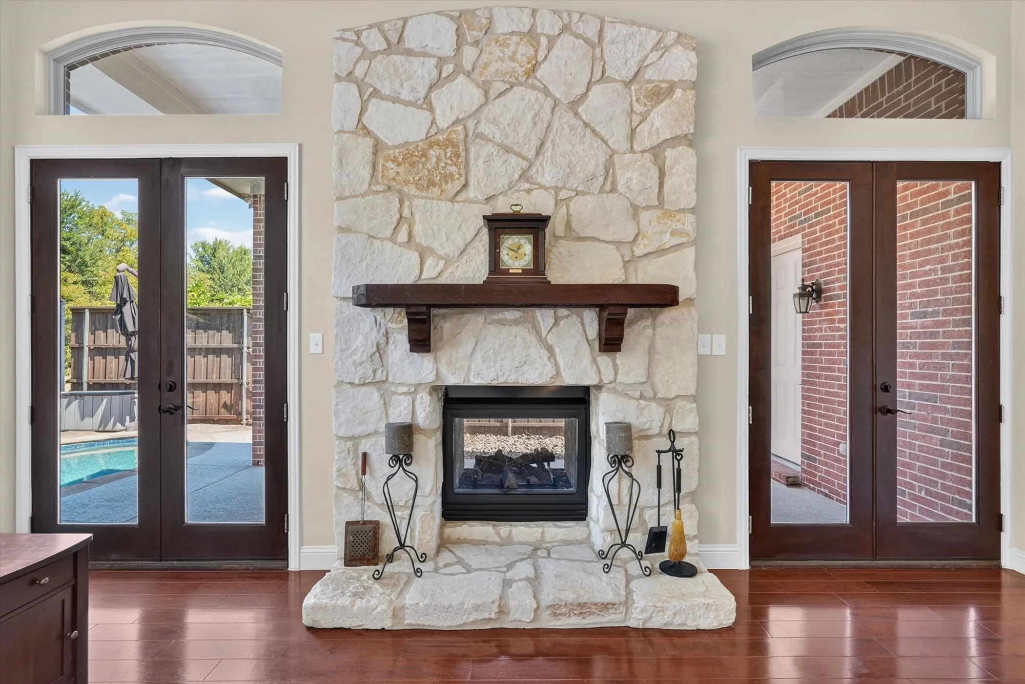 Look at this beautiful stone fireplace with a double sided firebox, flanked by the two beautiful 8 foot french doors. Simply stunning!