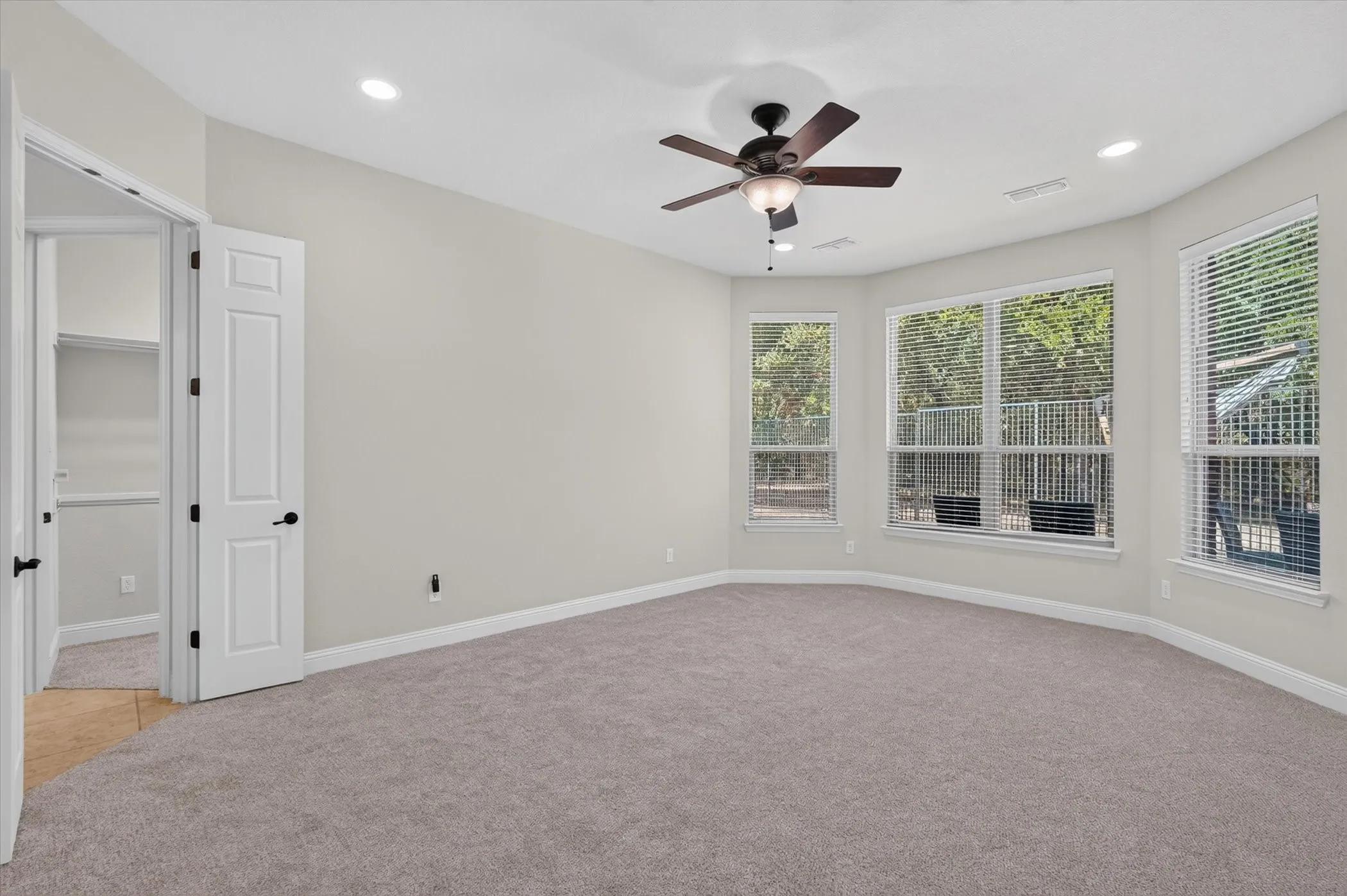 The primary bedroom featuers a bowed wall of windows overlooking the pool.