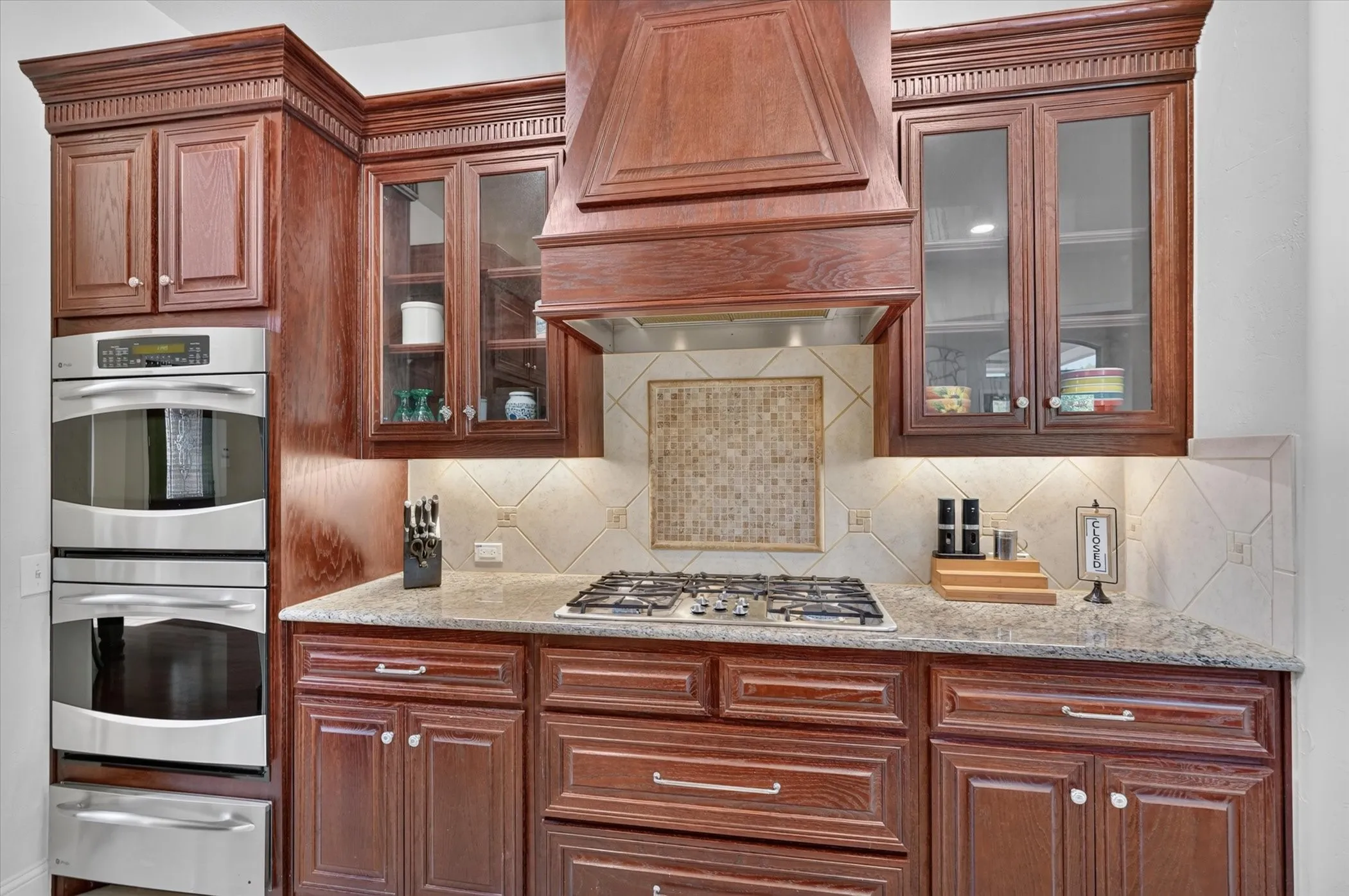 Two wall ovens, a warming drawer, and a gas cooktop finish out this well-appointed kitchen