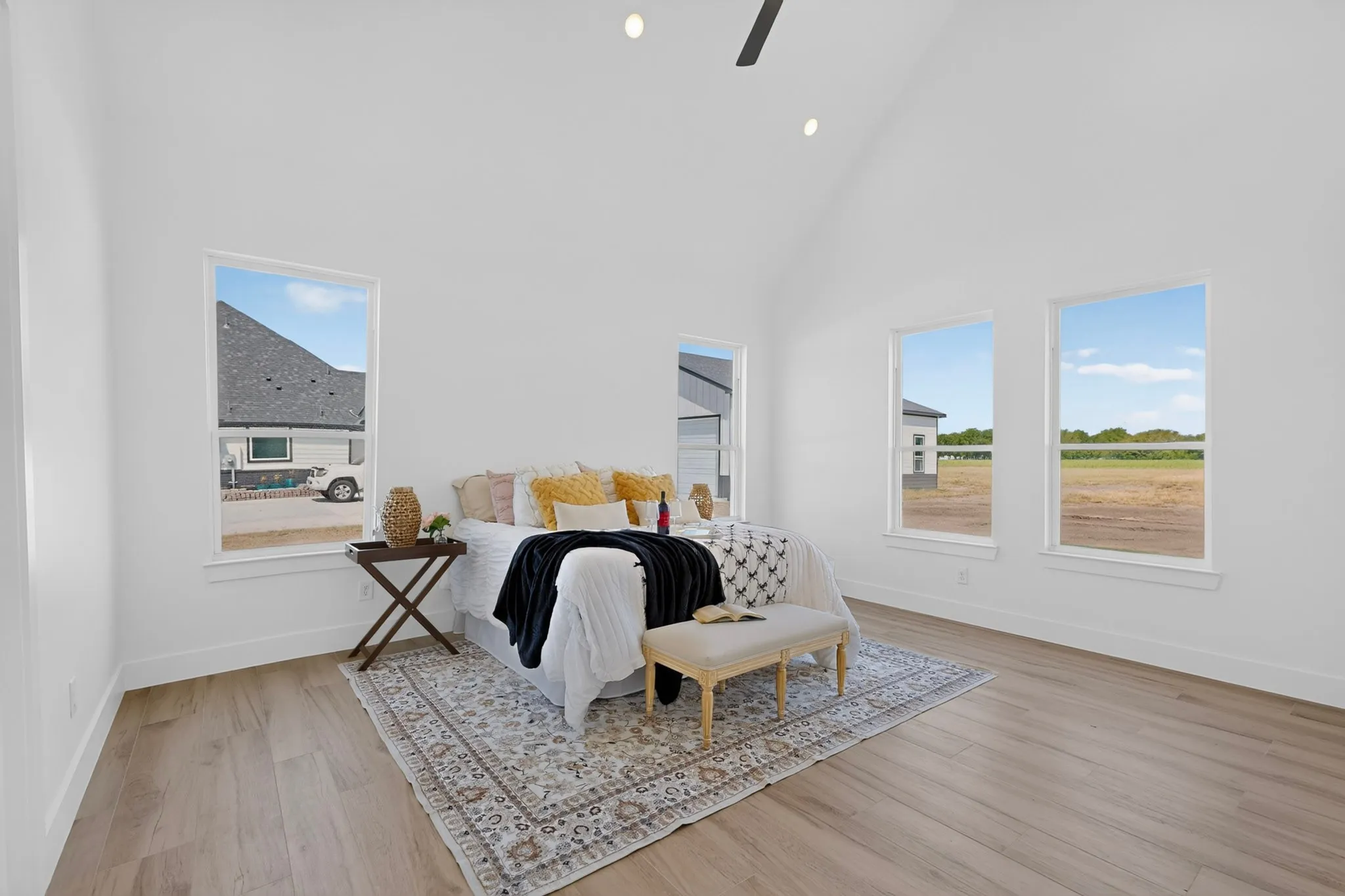 Vaulted ceiling with recessed lighting, large windows, wood-finish flooring, and a ceiling fan