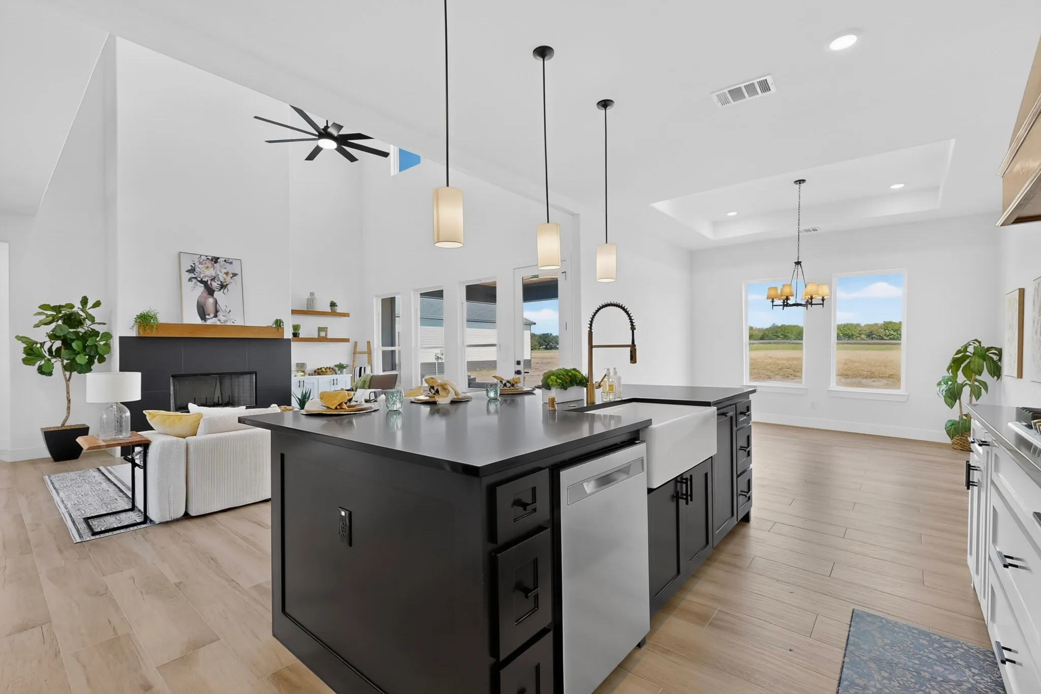 Spacious kitchen island with a farmhouse sink, stainless steel dishwasher, and pendant lighting