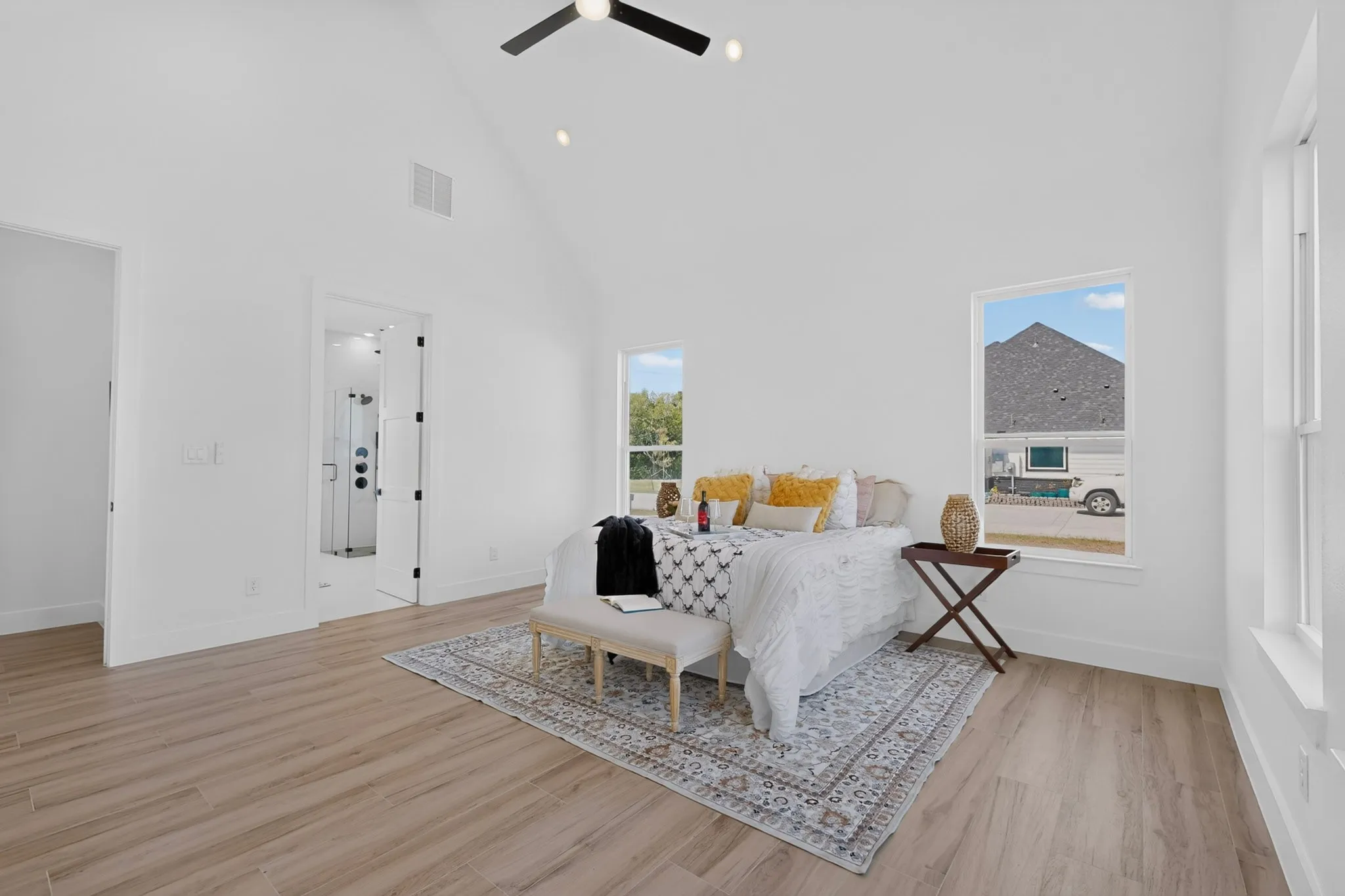 Vaulted ceiling with a ceiling fan, recessed lighting, wood-finish flooring, and white window frames