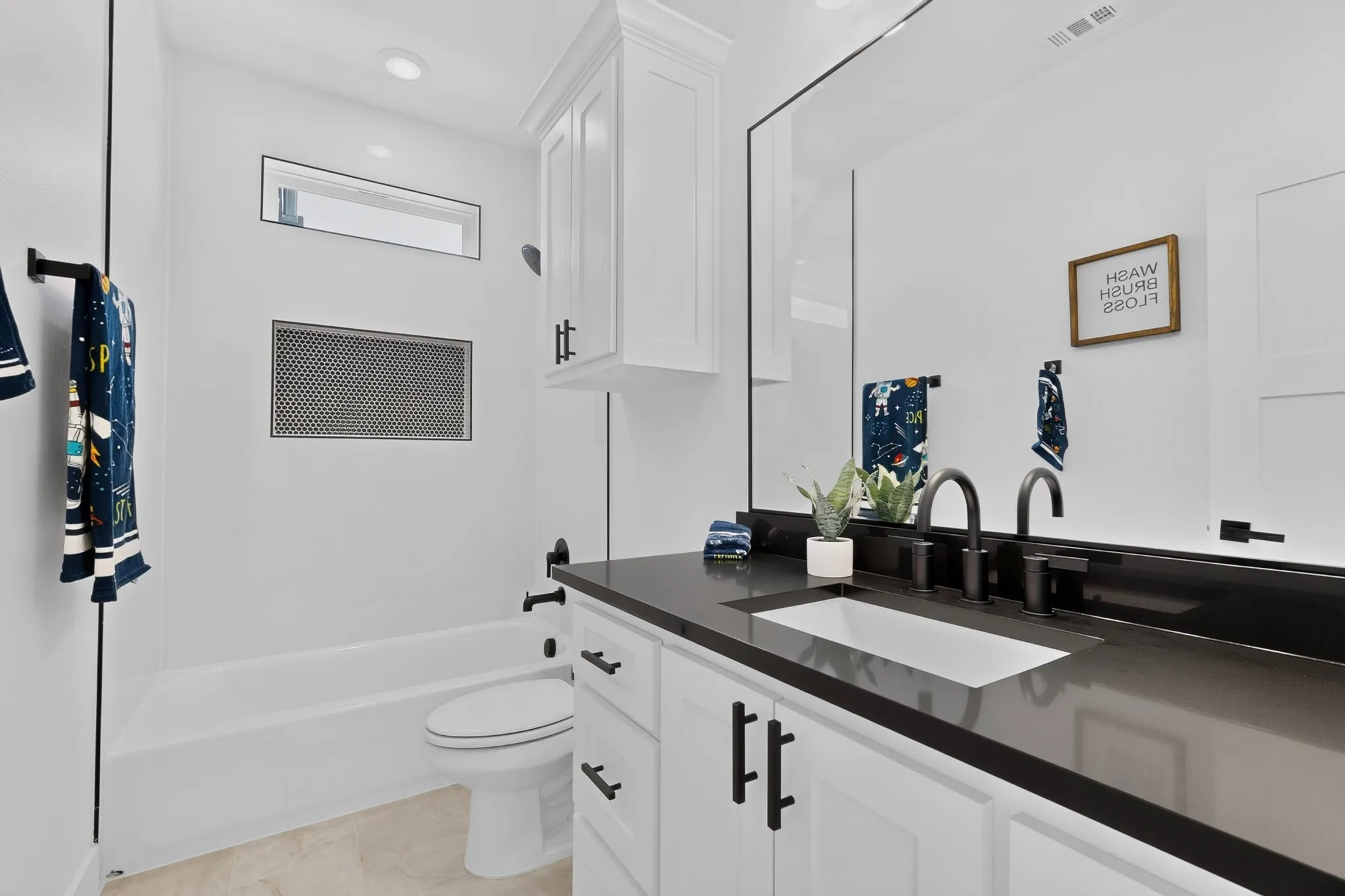 Vanity with a dark countertop, undermount sink, and matte black faucet