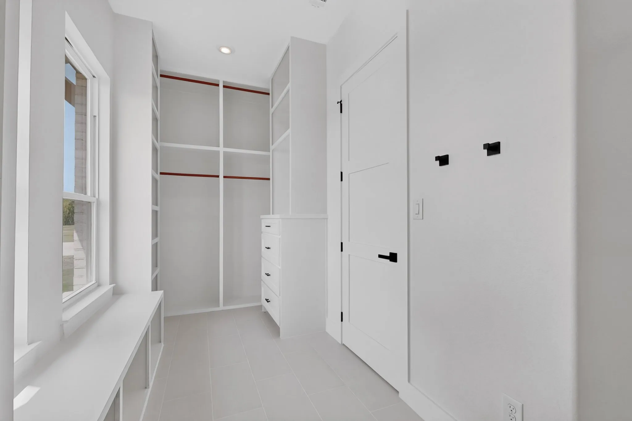 Built-in shelving, integrated drawers, recessed lighting, window bench, and an interior panel door with matte black hardware