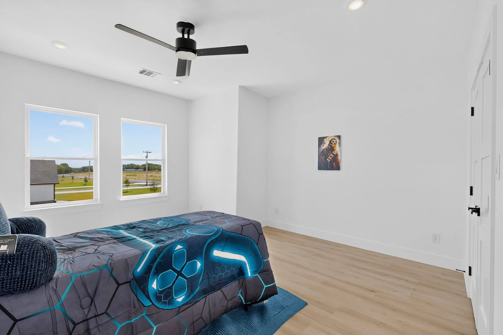 Recessed lighting, wood-finish flooring, two windows with white trim, and a black ceiling fan with light fixture