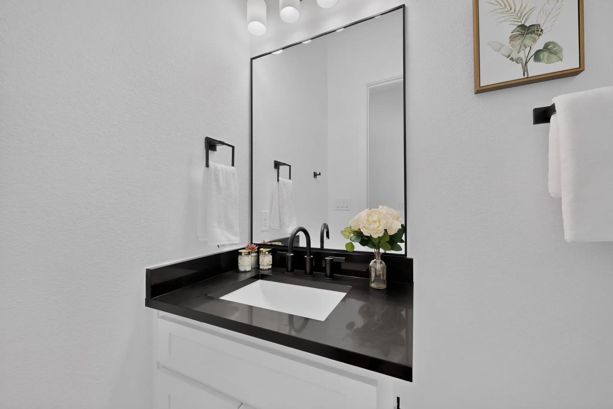 Vanity with dark countertop, integrated rectangular sink, and matte black faucet