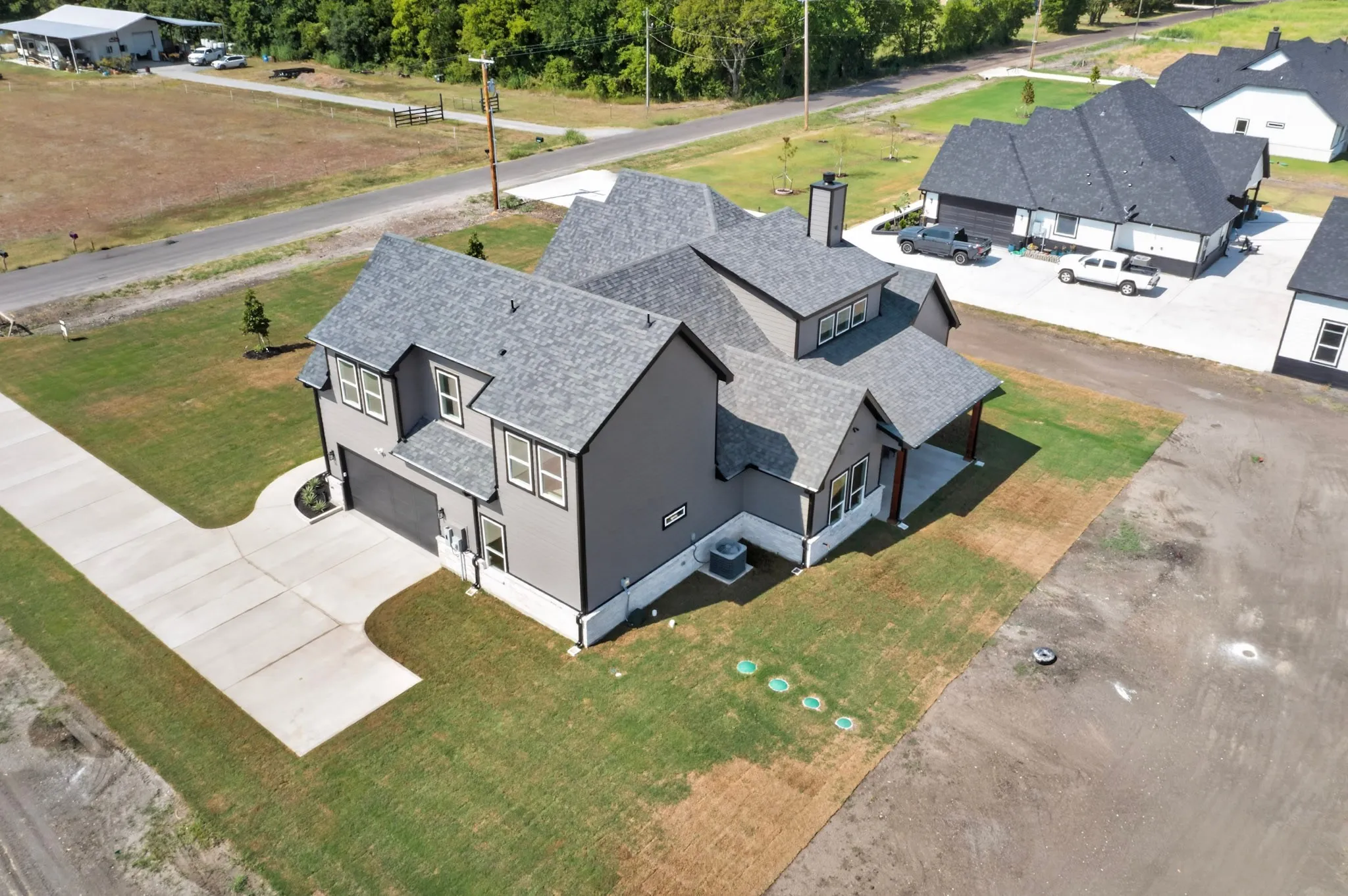 Two-story residence with a gray exterior finish, gray shingle roofing, attached garage, concrete driveway, and covered entry