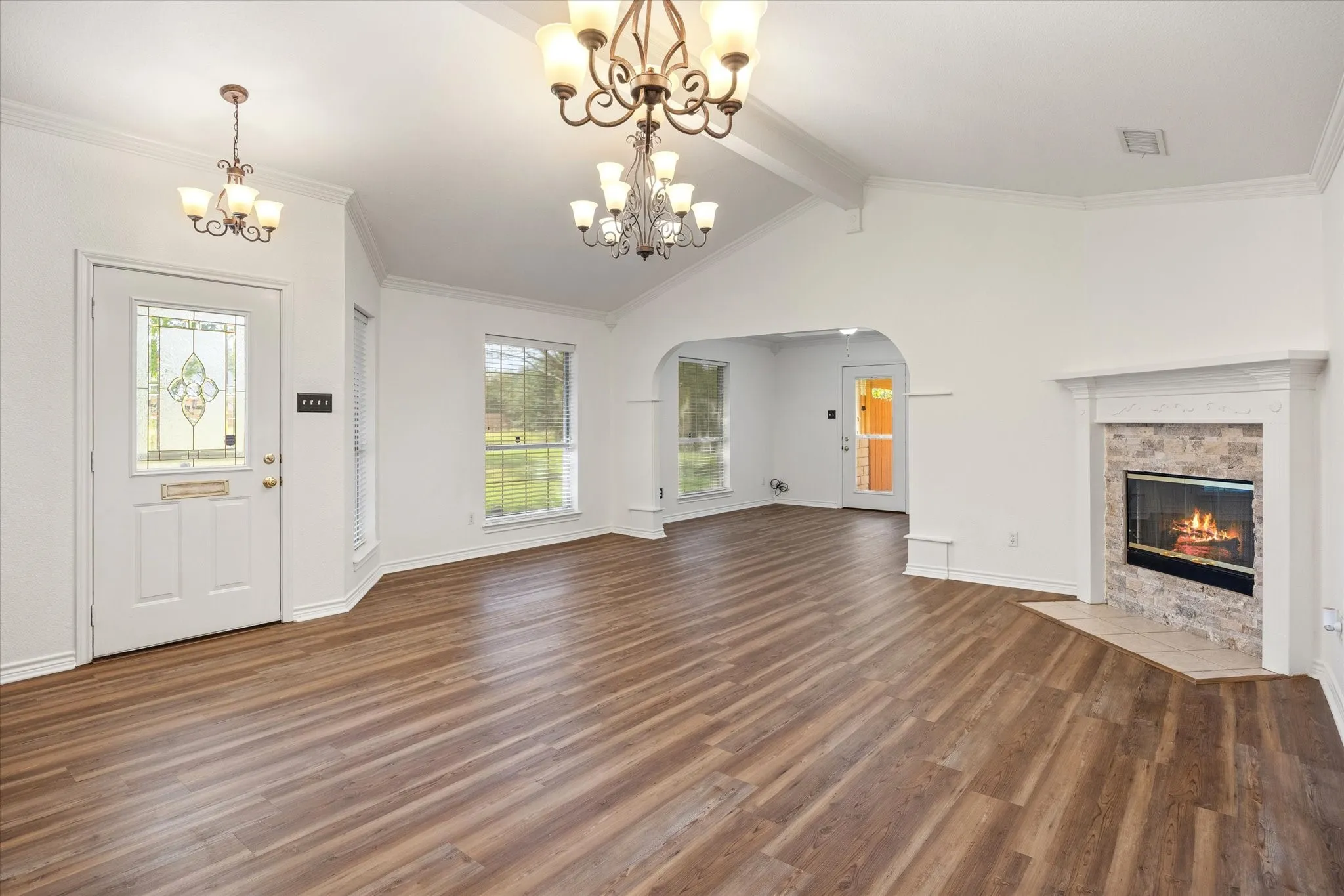Living room looking towards entry and corner fireplace with tile surround and luxury vinyl plank flooring.