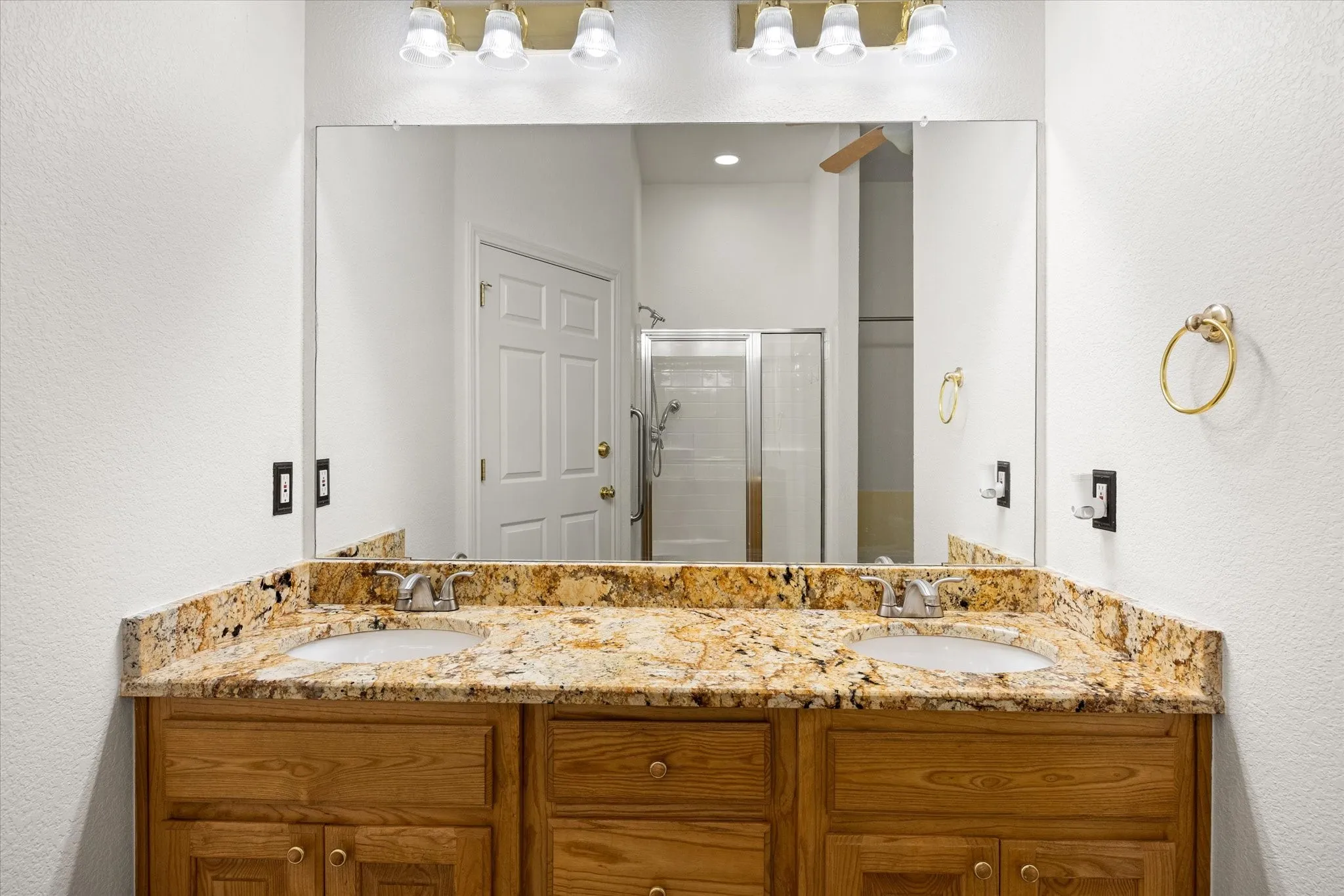 Dual vanity with wood-finish cabinetry, under-mount sinks, and a stone countertop
