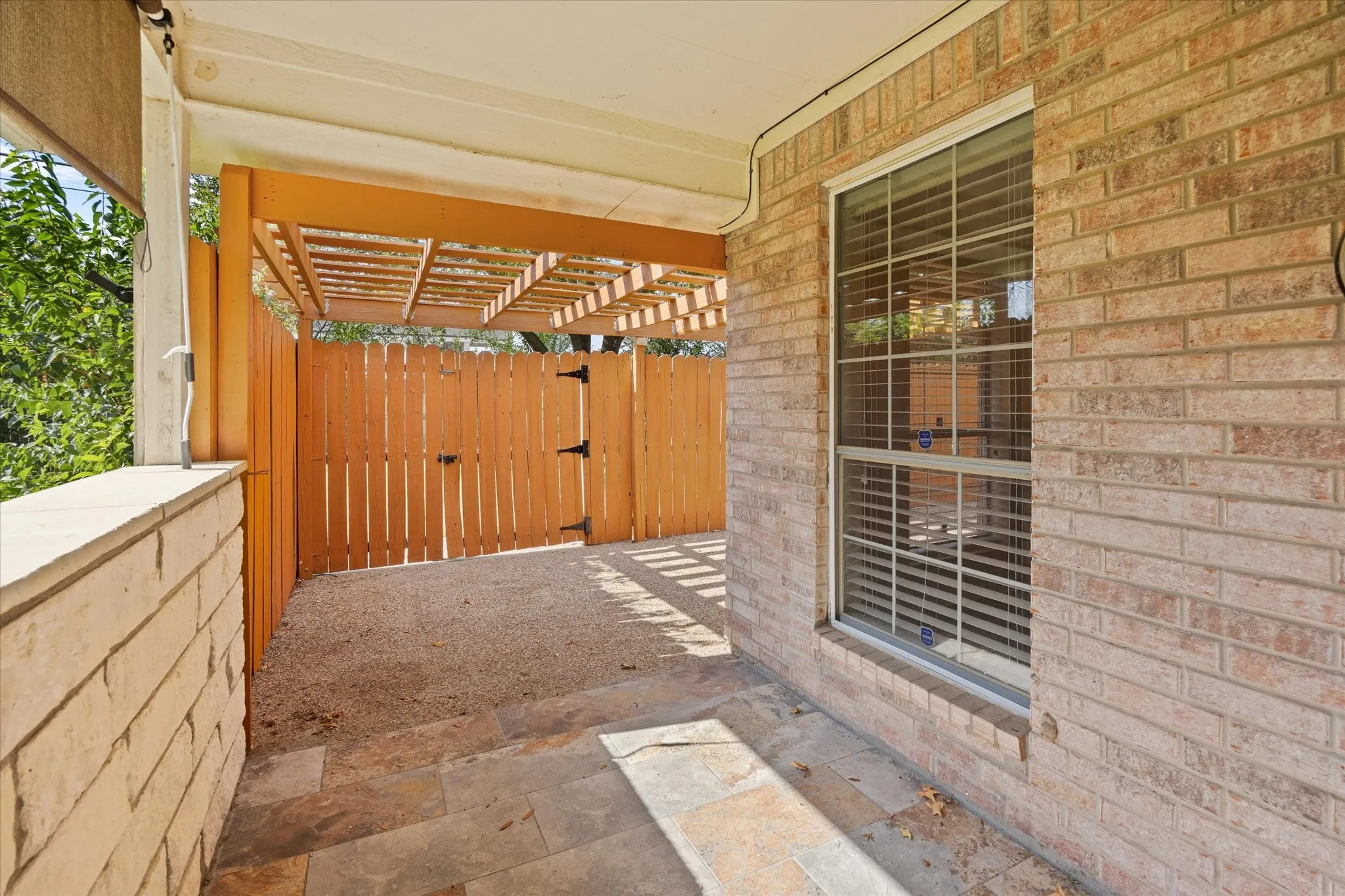 Covered patio featuring a wood pergola and stone wall and slate tile flooring