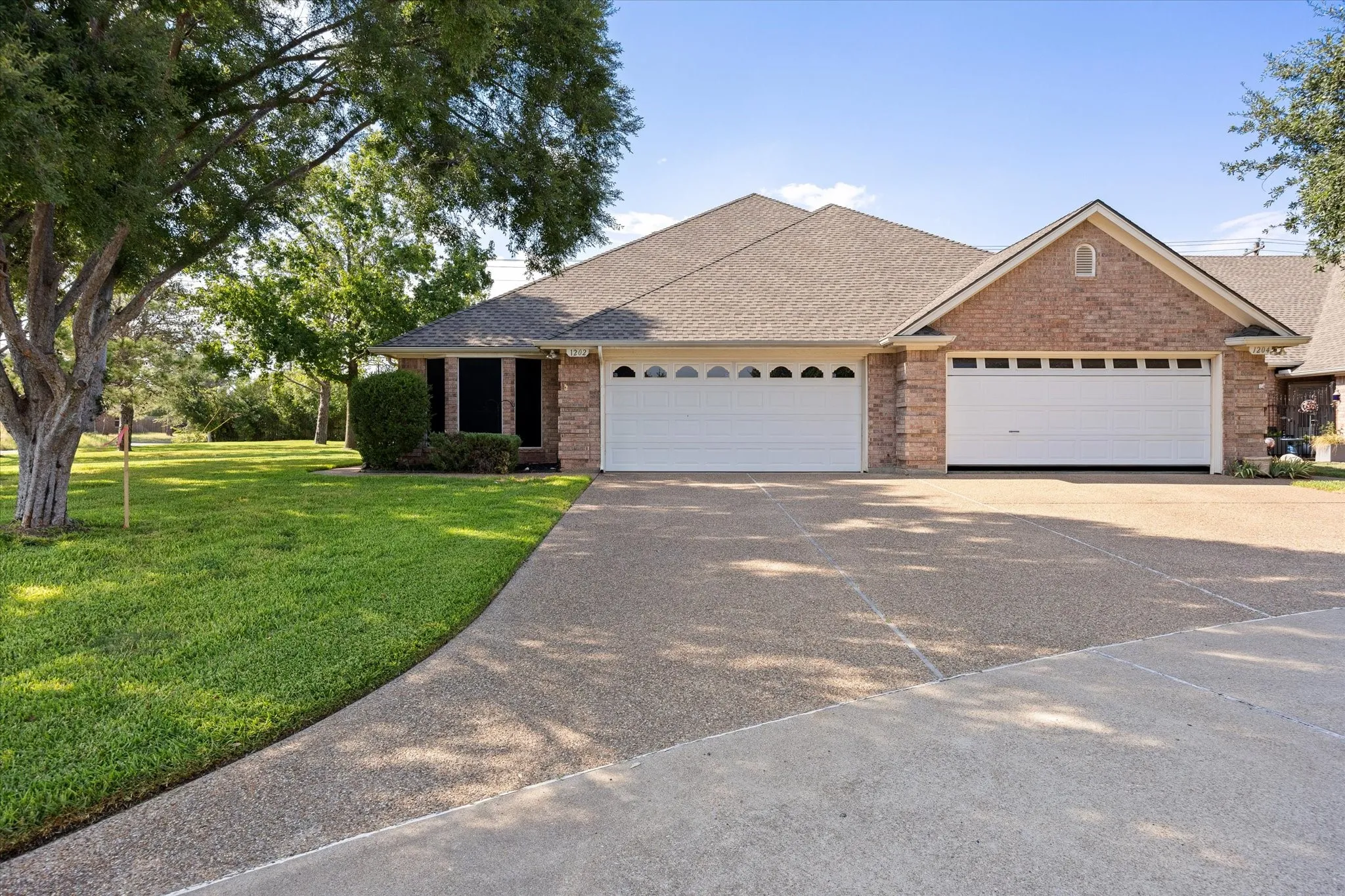Brick facade, composition shingle roof, and an attached two-car garage